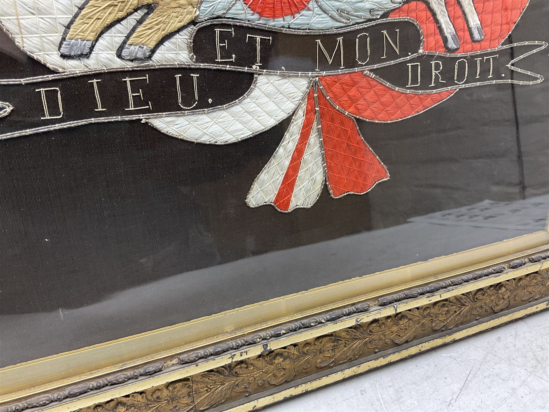 Early 20th century silk needlework panel, depicting a ship in full sail and Royal Coat of Arms to centre, with red and white ensigns to either side, lion and unicorn below with quote 'Dieu Et Mon Droit', upon a black silk ground within gilt frame, H59cm