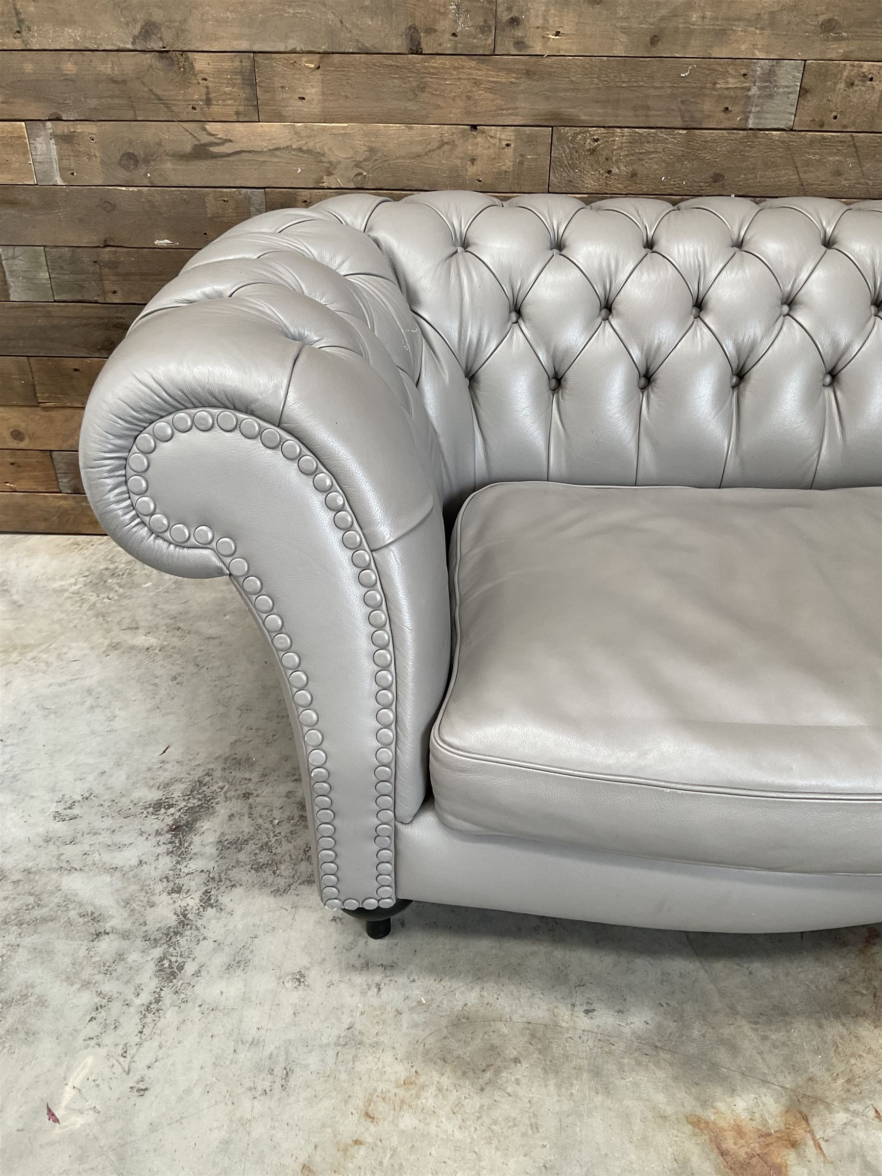 Three seat Chesterfield sofa, upholstered in grey buttoned leather - damaged leg