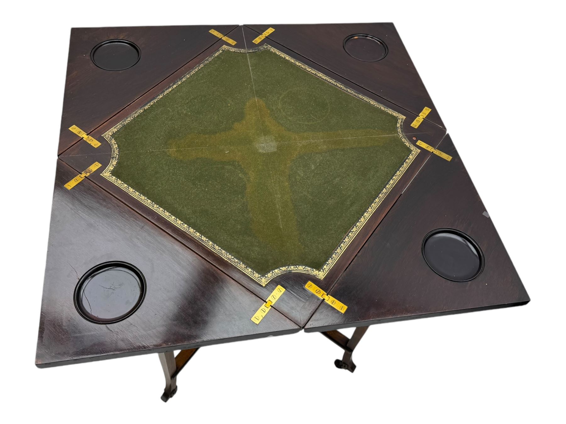 Victorian rosewood envelope games table, the moulded square top with four triangular hinged leaves, revealing inset baize playing surface and sunken counter wells, fitted with single frieze drawer, on square tapering supports united by x-framed stretchers and turned central column, on brass and ceramic castors 