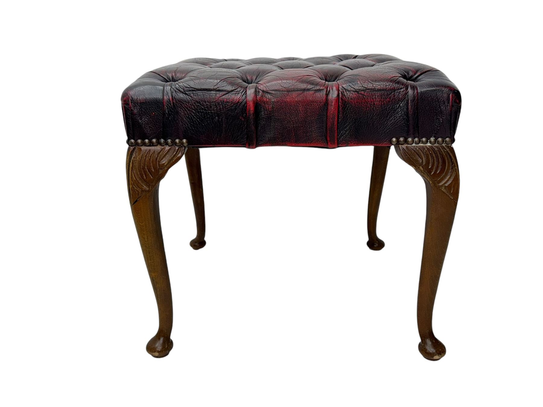 Chesterfield three-seat sofa, traditional shaped upholstered in deeply buttoned dark red leather; together with similar footstool 