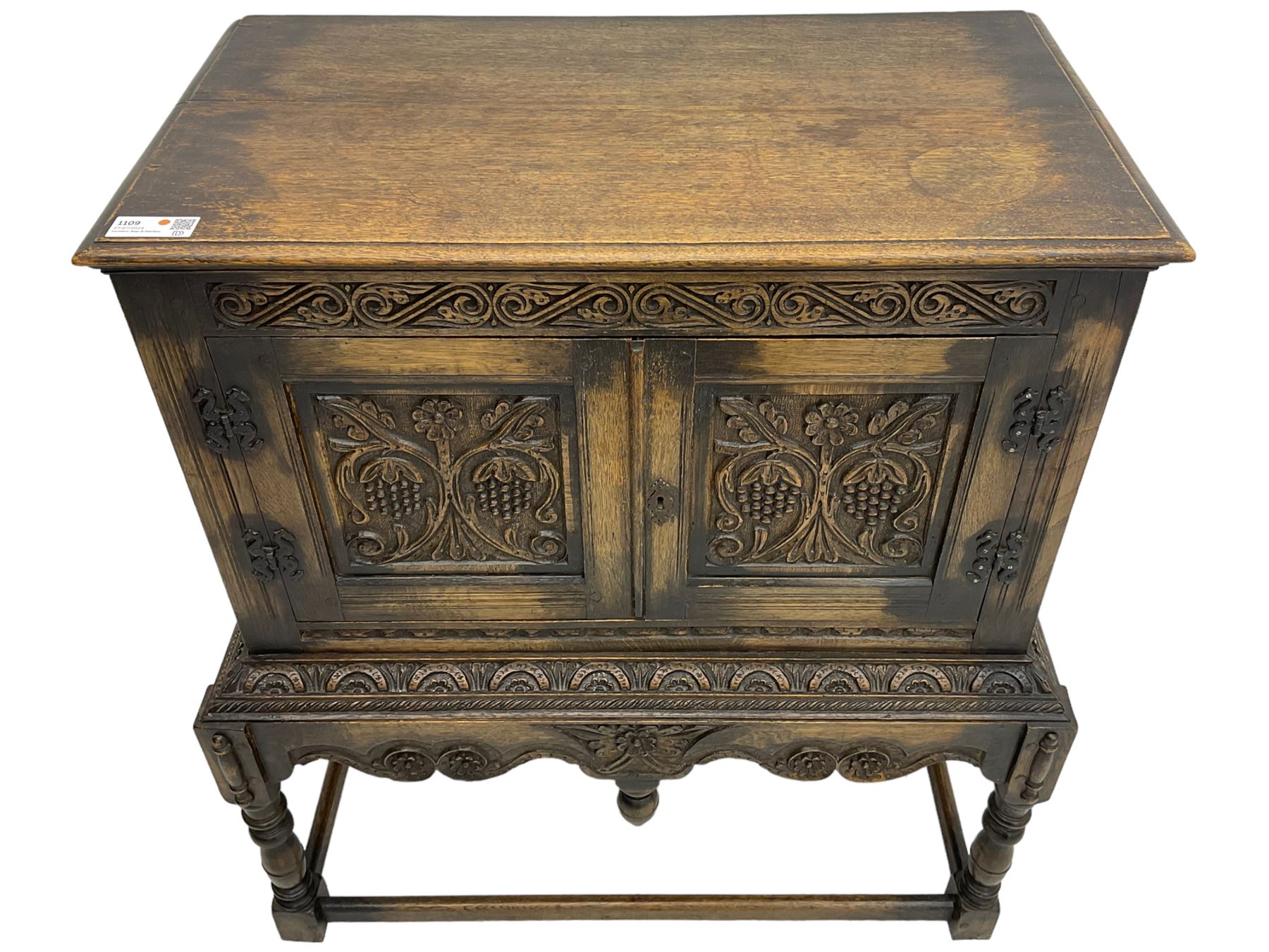 Jacobean Revival carved oak cupboard, moulded rectangular top over S-scroll carved frieze and two doors, the panelled doors carved with stylised plant motifs, on stand decorated with lunettes and shaped apron with hanging turned pendant, on turned supports united by stretchers 