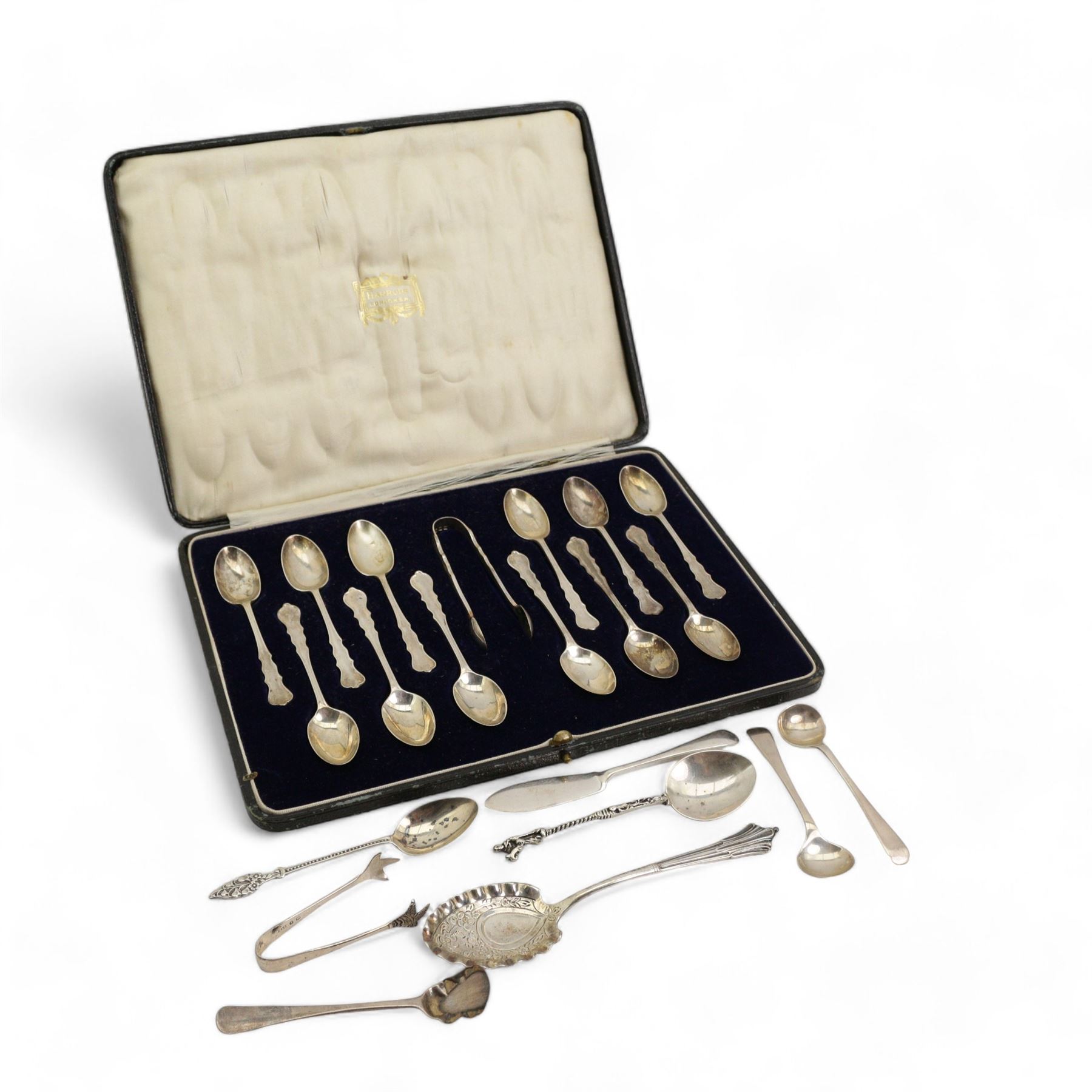 Set of twelve silver coffee spoons and tongs with shaped stems, London 1922 in Harrods case, silver preserve spoon and other silver cutlery 