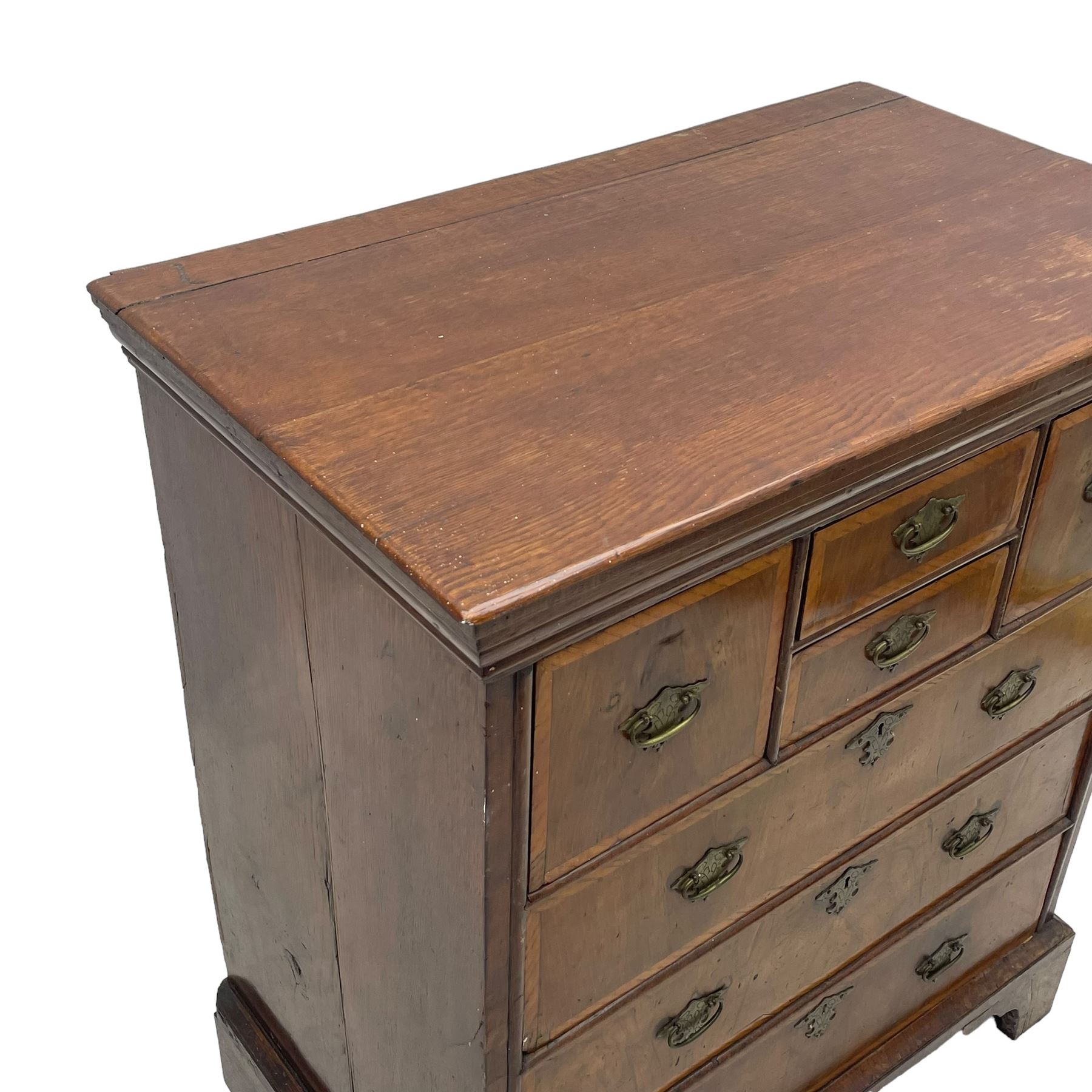 18th century oak and walnut chest, fitted with four small over three long drawers with figured walnut facias, brass handles and plates with engraved decoration, on bracket feet