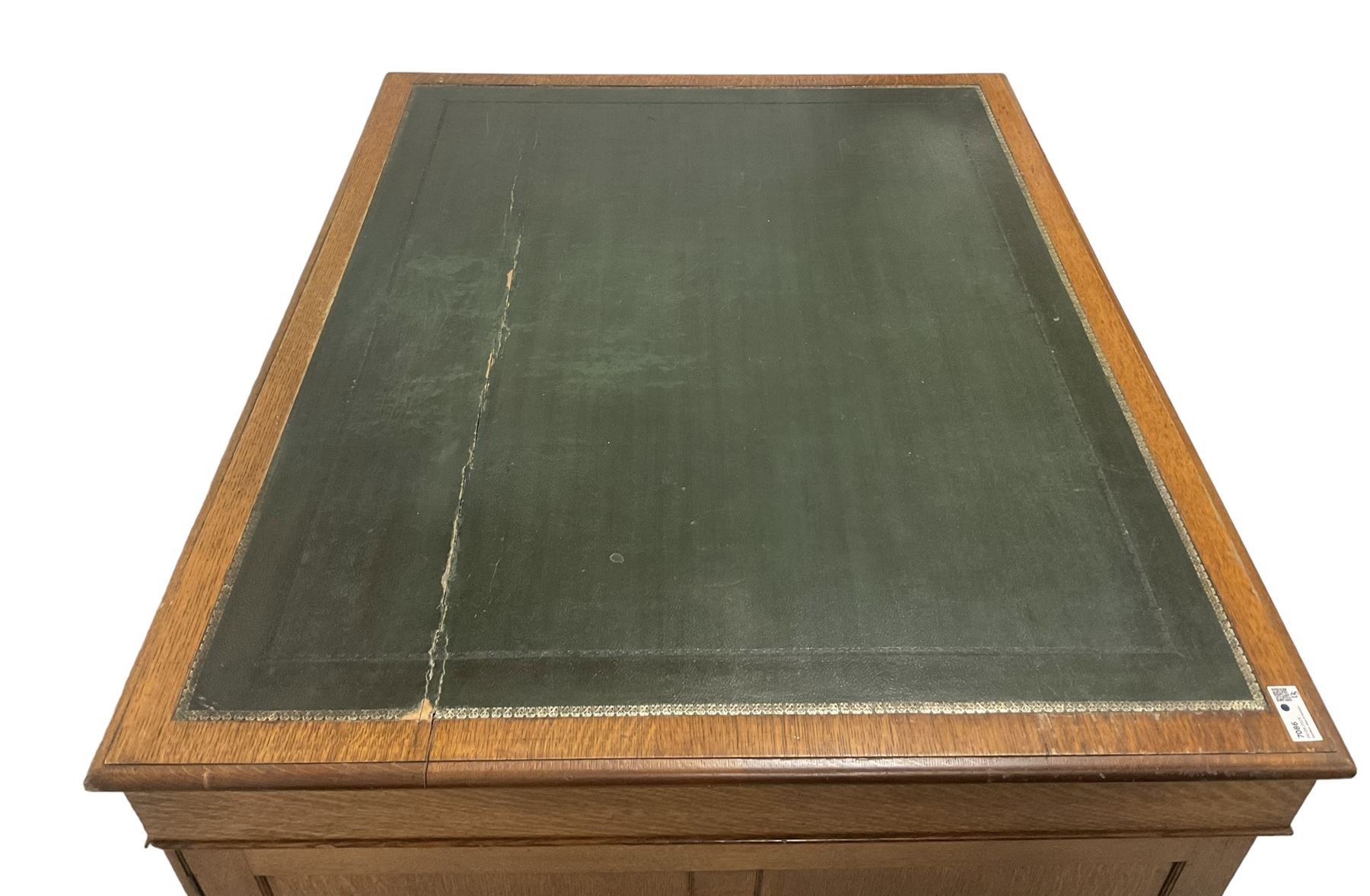 Late 19th century twin pedestal oak partner's desk, rectangular top with inset green leather writing surface, fitted with nine graduating drawers to each side, the rear drawers enclosed by panelled cupboards