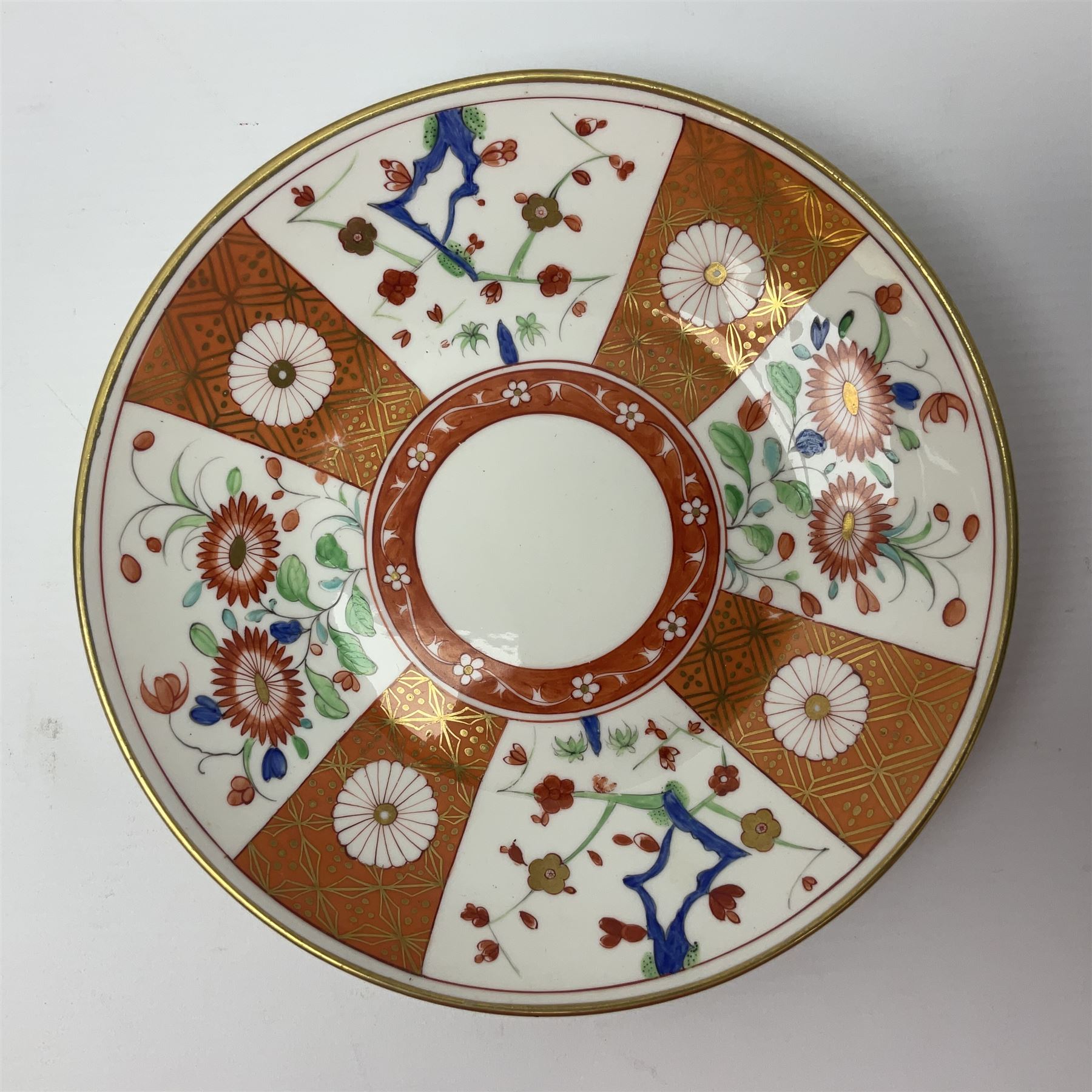 Three 18th century Worcester desert dishes, the first example decorated in the Scarlet Japan pattern, circa 1790, painted with alternating panels of Kakiemon style prunus blossom and chrysanthemum, and orange ground panels with gilt fret detail, D19cm, the second example, circa 1770, decorated with Kakiemon style chrysanthemums and foliage within shaped reserves upon a blue scale ground, with fretted square pseudo mark beneath, D19cm, and the third, circa 1770, painted with polychrome floral sprays and sprigs, D20cm