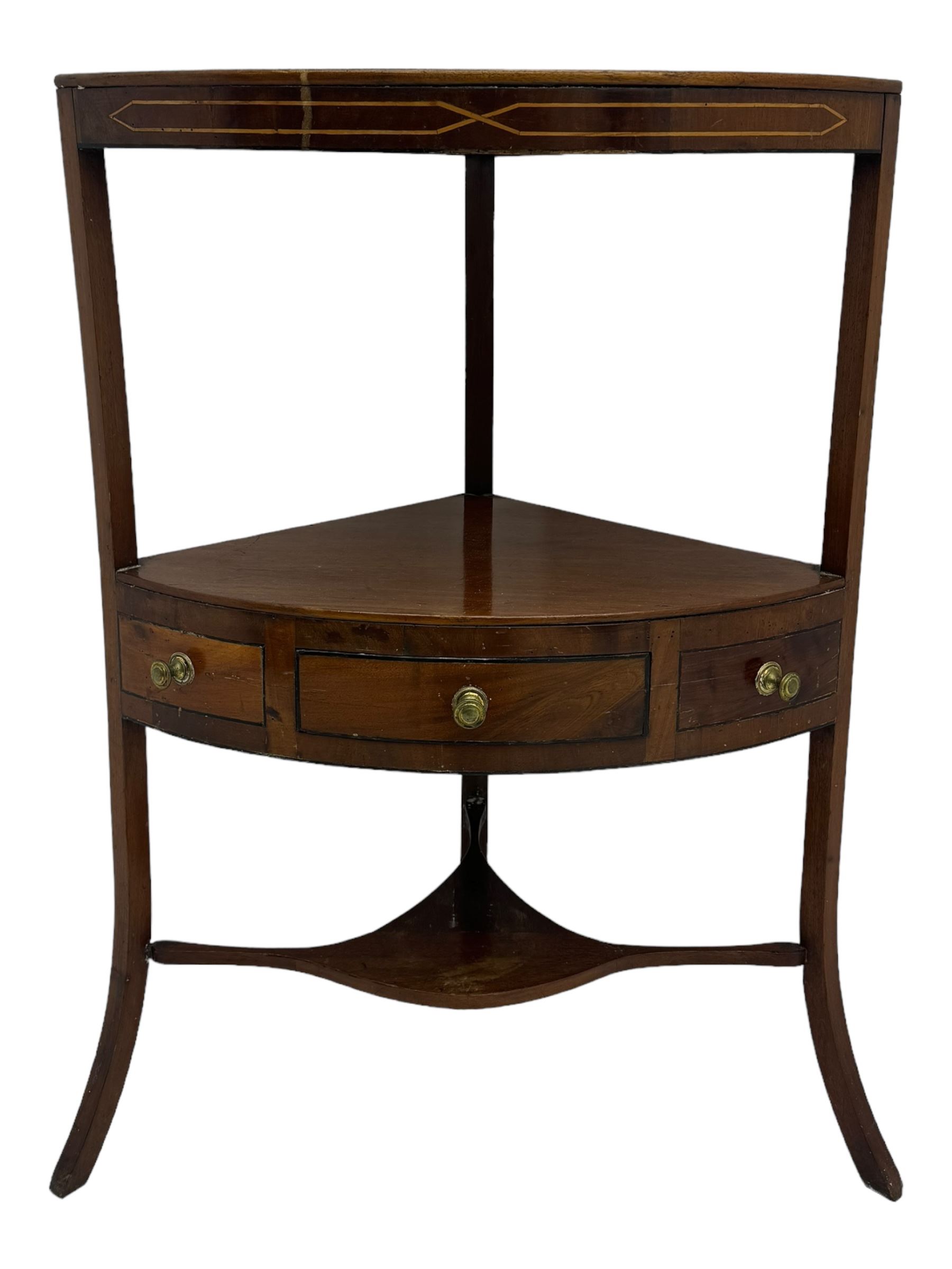 George III mahogany two-tier corner washstand, the inlaid top with geometric border, central drawer flanked by two faux drawers each with brass pull handle, on splayed supports united by shaped under-tier