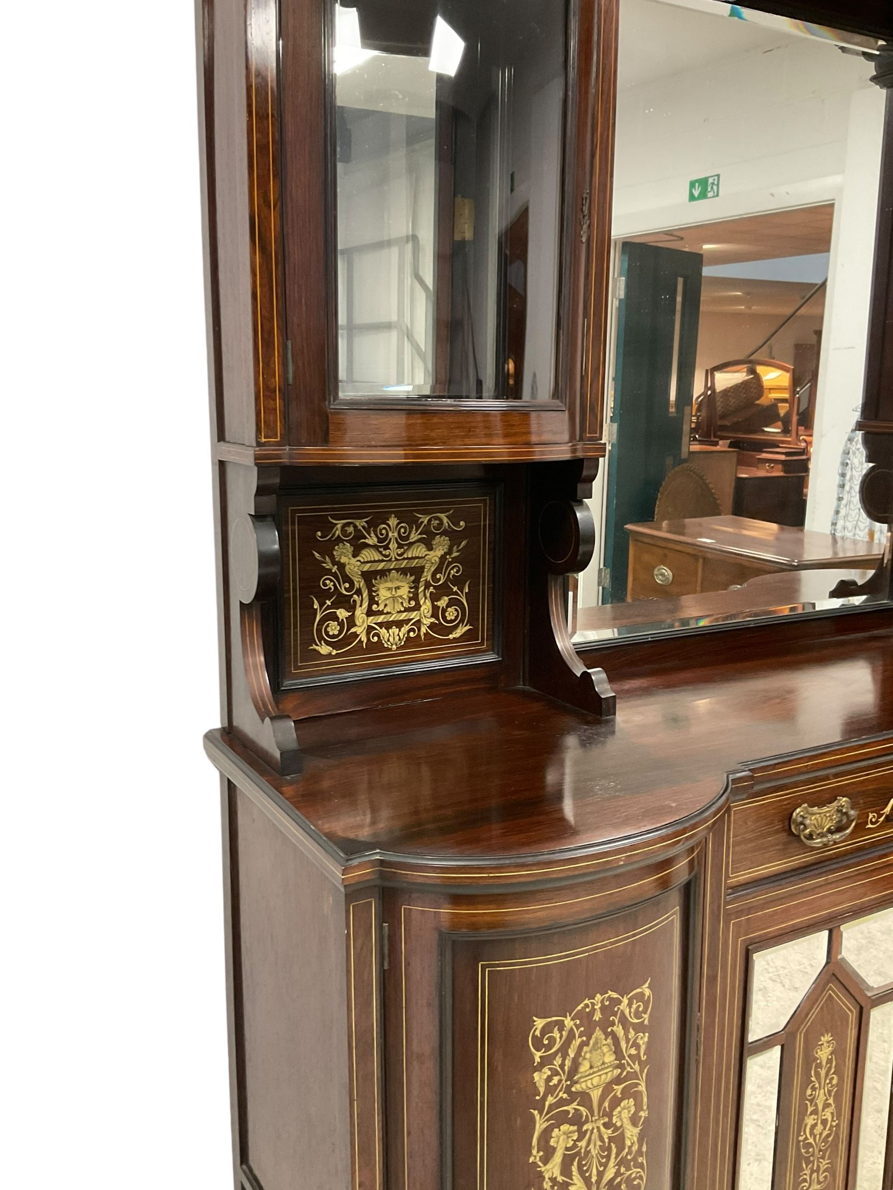 Late Victorian inlaid rosewood mirror back sideboard, shaped cresting rail decorated with scrolling foliate ivorine inlays, over rectangular bevelled mirror, flanked by bow-front glazed cupboards over inlaid 'green man' motifs, the base fitted with single drawer and cylindrical cupboards flanking a mirror panelled cupboard, on square tapering supports