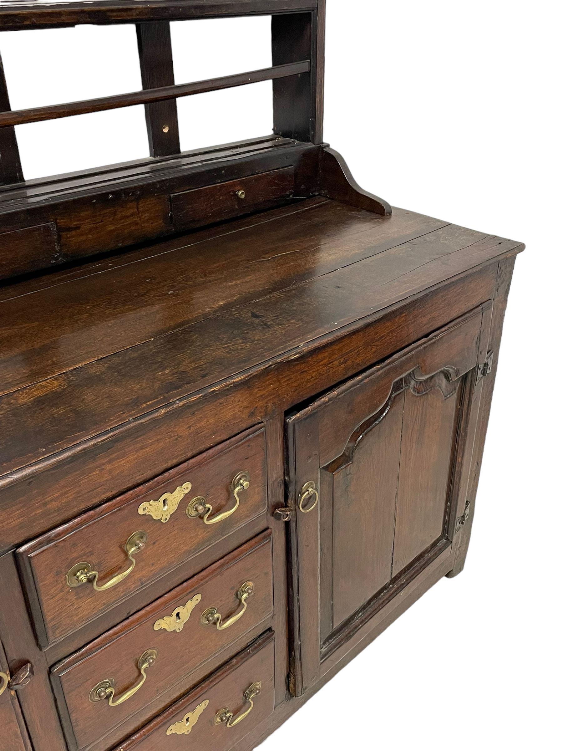 18th century oak dresser, projecting cornice over three heights plate rack with three small drawers, rectangular ovolo-moulded top over three central drawers and two flanking cupboards, enclosed by fielded panelled doors, on stile supports 