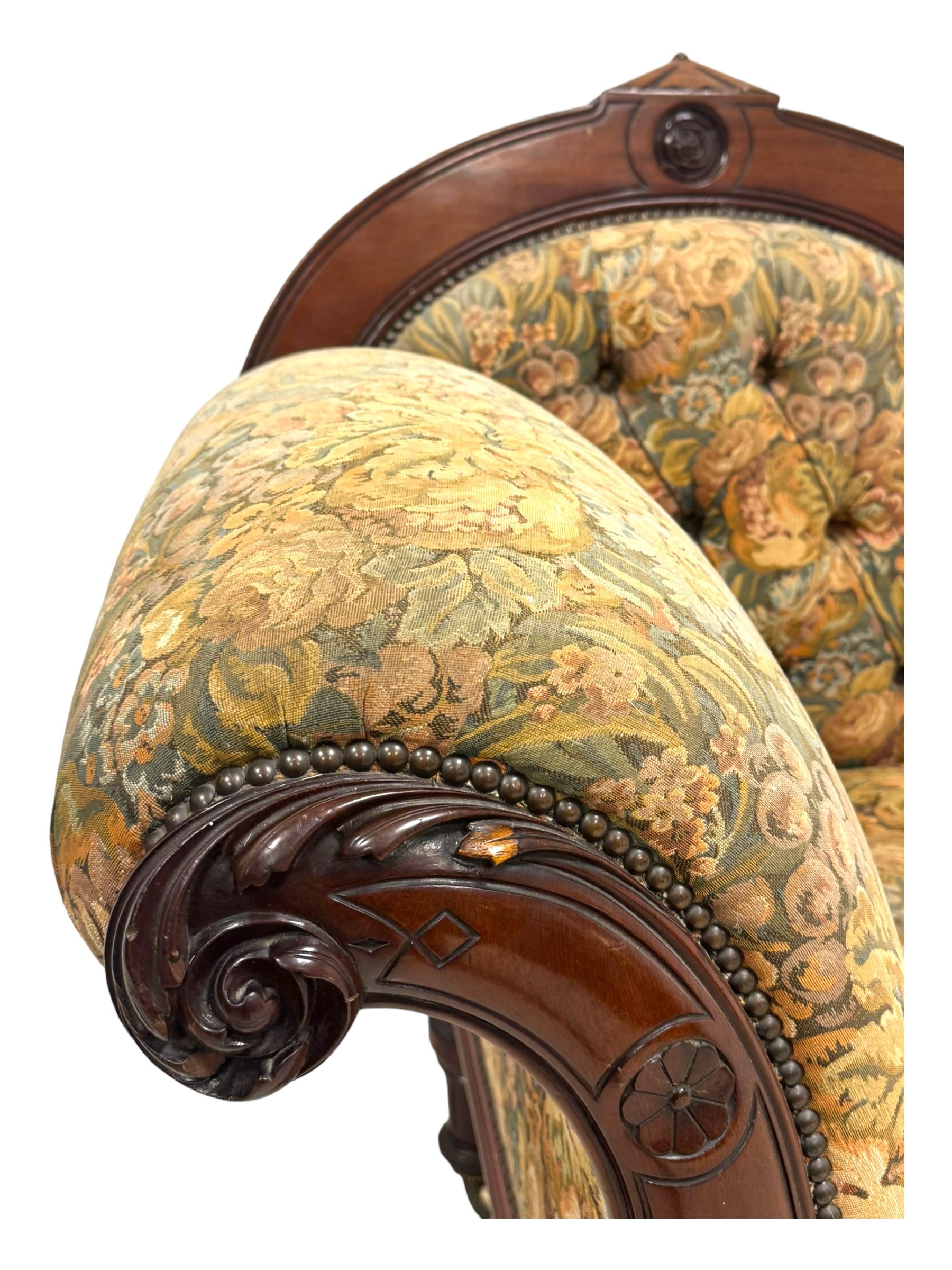 Victorian Aesthetic Movement mahogany framed chaise longue, shaped carved back over acanthus scrolled arm terminal, upholstered in floral patterned tapestry fabric with sprung seat, on turned and fluted supports with castors