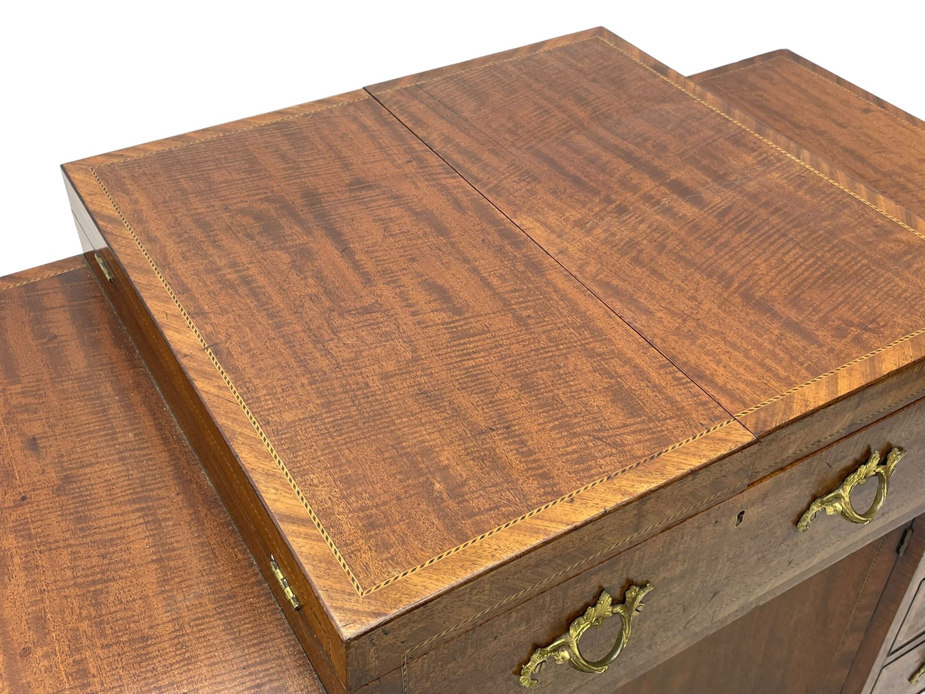 Late 19th century mahogany and satinwood dressing chest, the raised middle section hinges to reveal an interior fitted with lidded compartments, removable tray, single drawer and glass scent bottles, lift-up bevelled mirror with adjustable hinged mechanism, fitted with a further eight cock-beaded graduating drawers and curved kneehole with double cupboard, square tapering supports on brass cups and castors, inlaid throughout with checkered stringing, ornate Rococo cast gilt metal handles