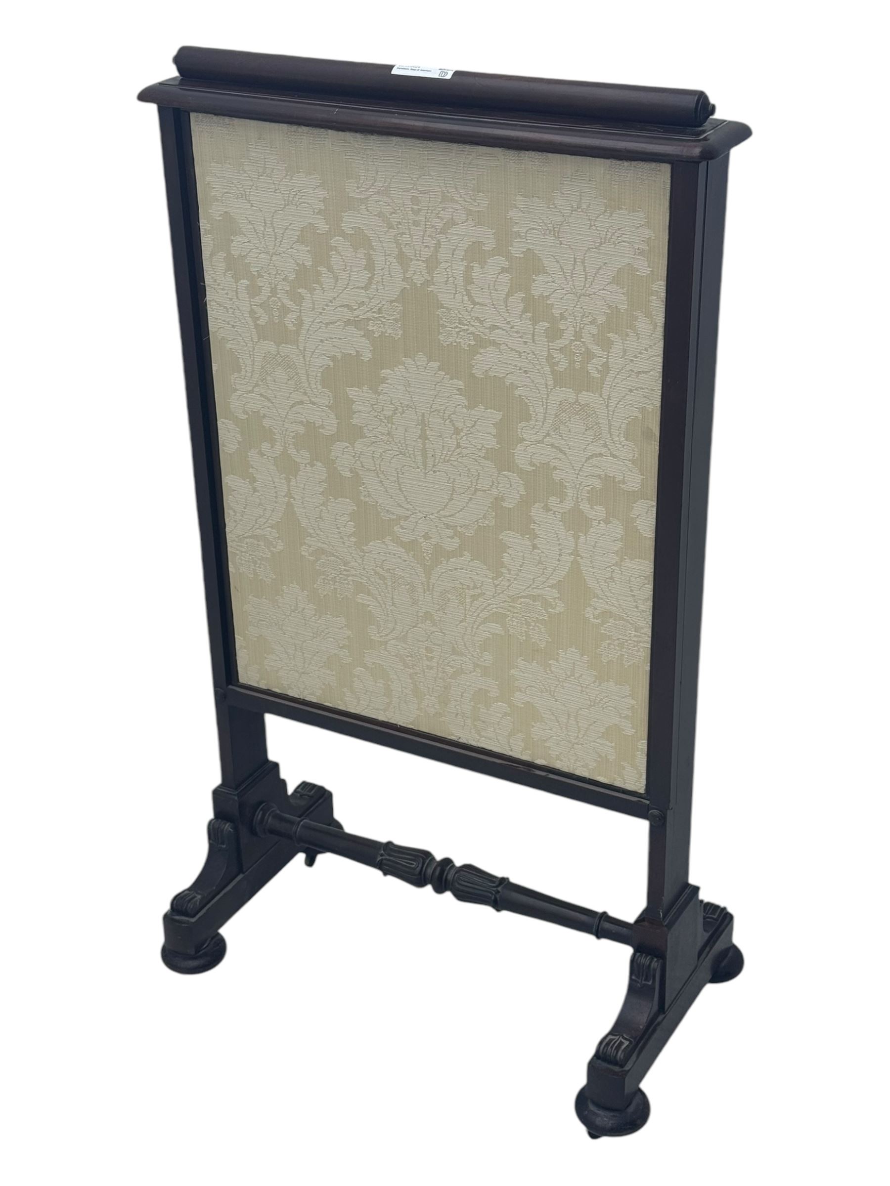 Early 19th century mahogany fire screen, upholstered in cream foliate pattern fabric, pull-up panel and sliding panel, raised on platforms united by turned and lappet carved stretcher, on compressed bun feet with castors 