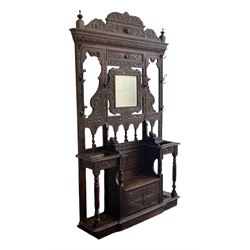 Victorian heavily carved oak hall-stand, moulded cornice with foliate carved decoration over bevelled mirror back, drop centre with hinged box seat flanked by stick or umbrella stands, scrolls and foliate carved decoration