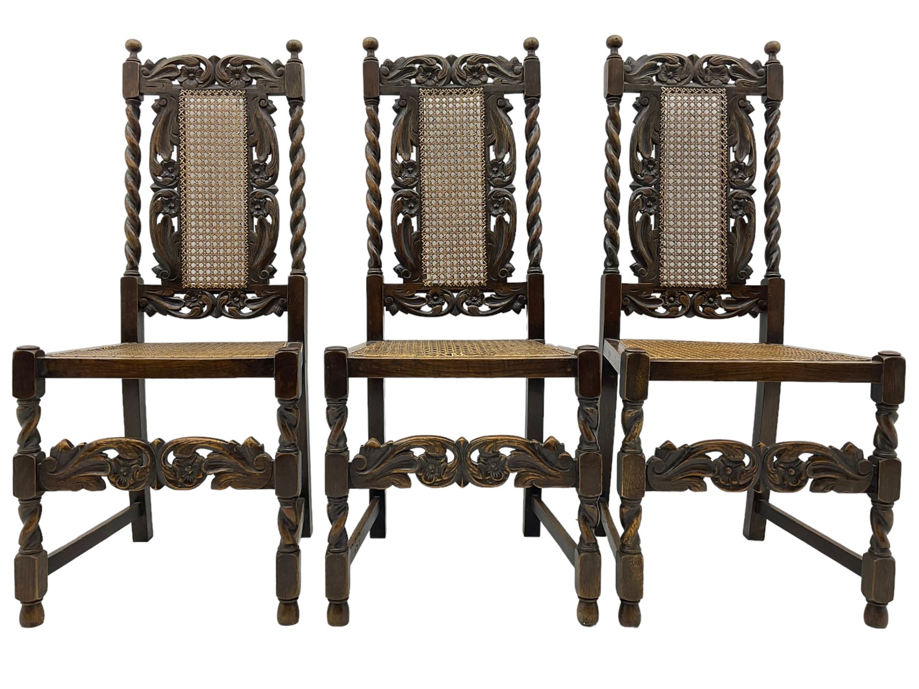 Set of seven (5+2) 19th century Carolean design oak dining chairs, scroll leaf and flower head carved cresting rail over spiral turned uprights and cane work back, the cane work seat on spiral turned supports united by plain stretchers, scrolled leaf carved middle rail 