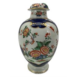 18th century Worcester tea caddy, of oval form and painted in the Kakiemon palette with reserves of flowers against a blue scale ground, H14cm together with a similar Worcester circular dish, painted with floral sprays, within a scalloped edge, blue crescent mark beneath, D19cm (2)