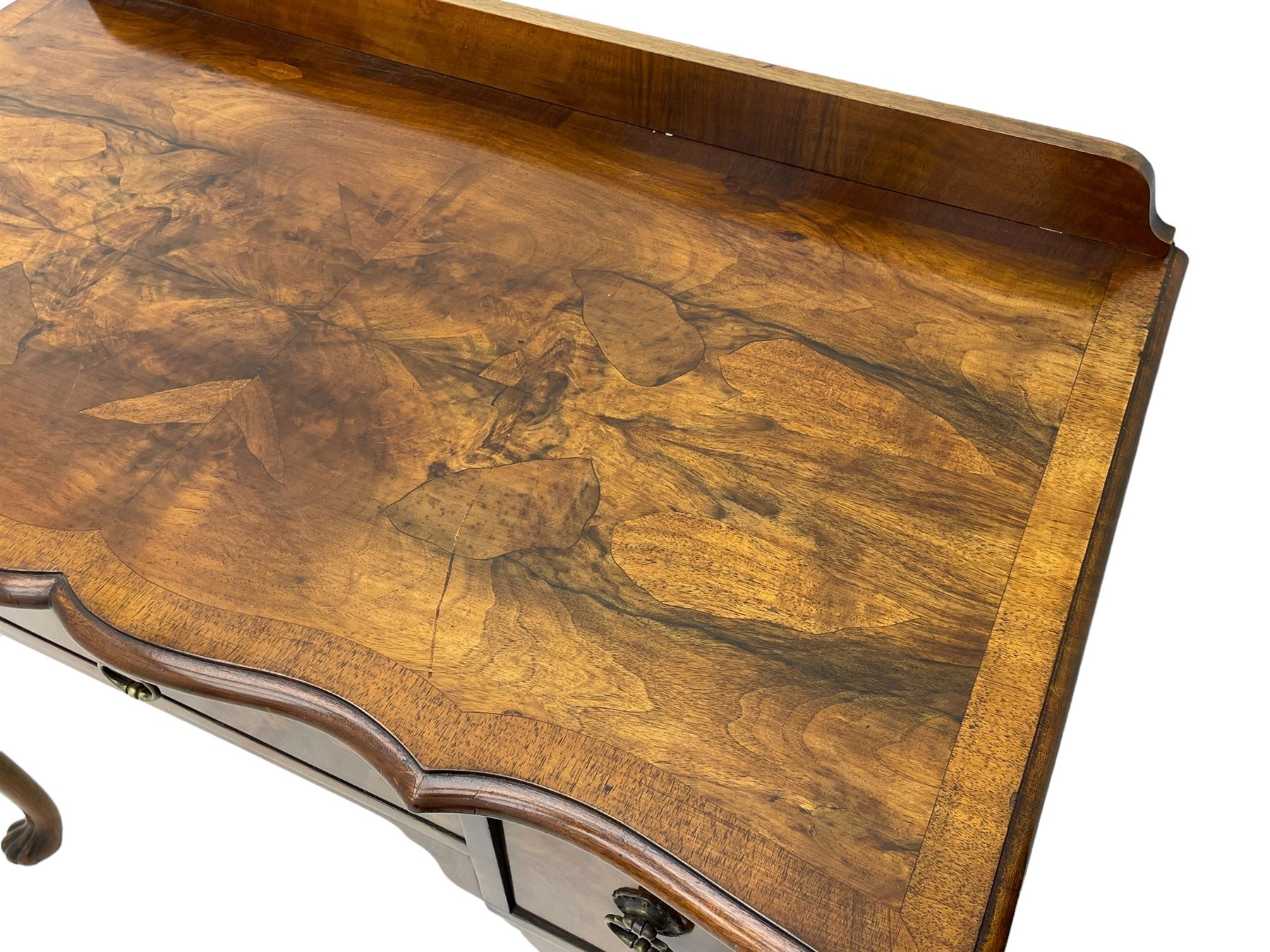 Mid-to-late 20th century figured walnut side table, raised back over figured top with cross banding and shaped front, fitted with three drawers, on cabriole supports with carved terminals 