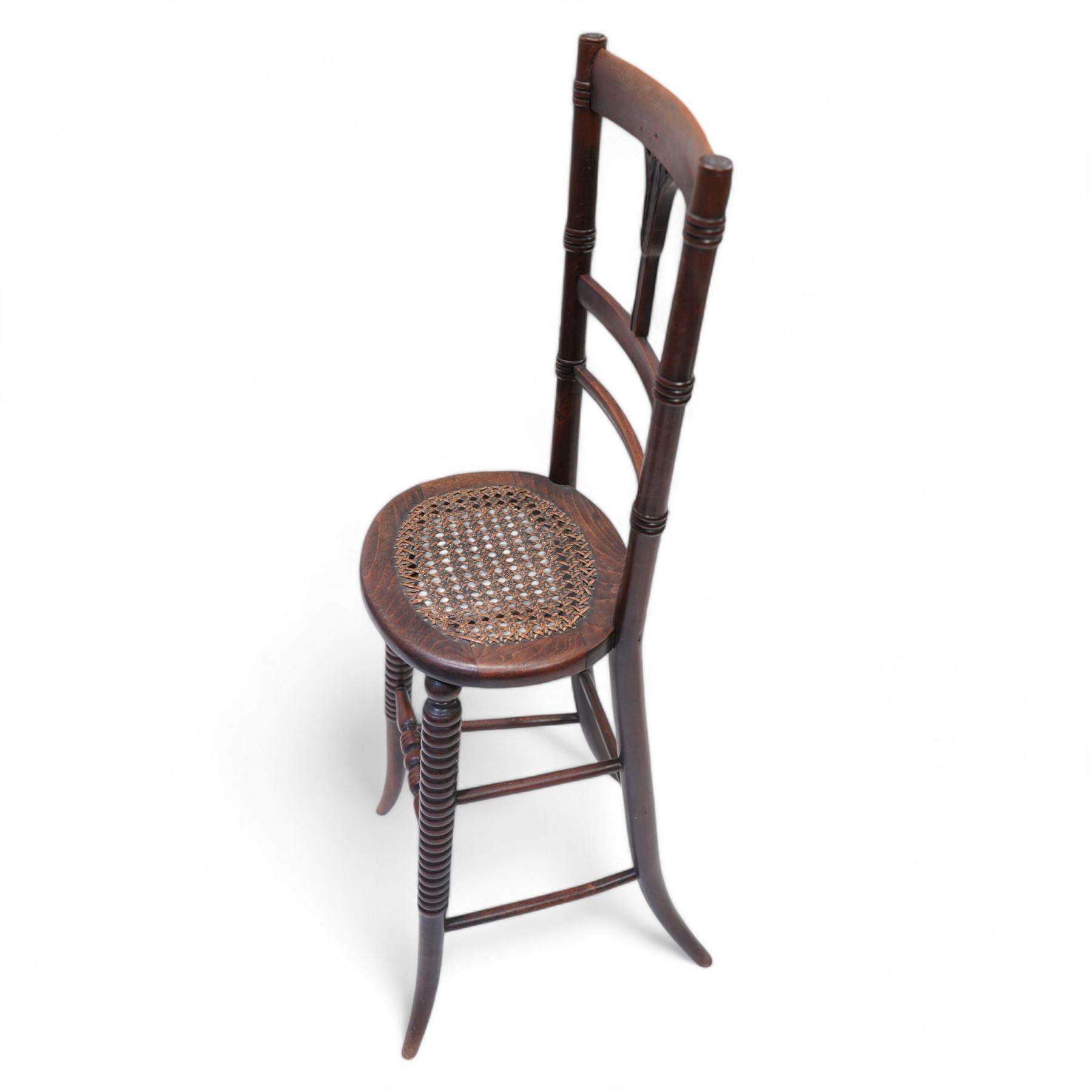 Regency beech framed child's correction chair, ring turned upright supports united by stretcher back carved with curled leaf motif, oval cane work seat, on rib turned supports terminating to splayed feet, united by turned stretchers 