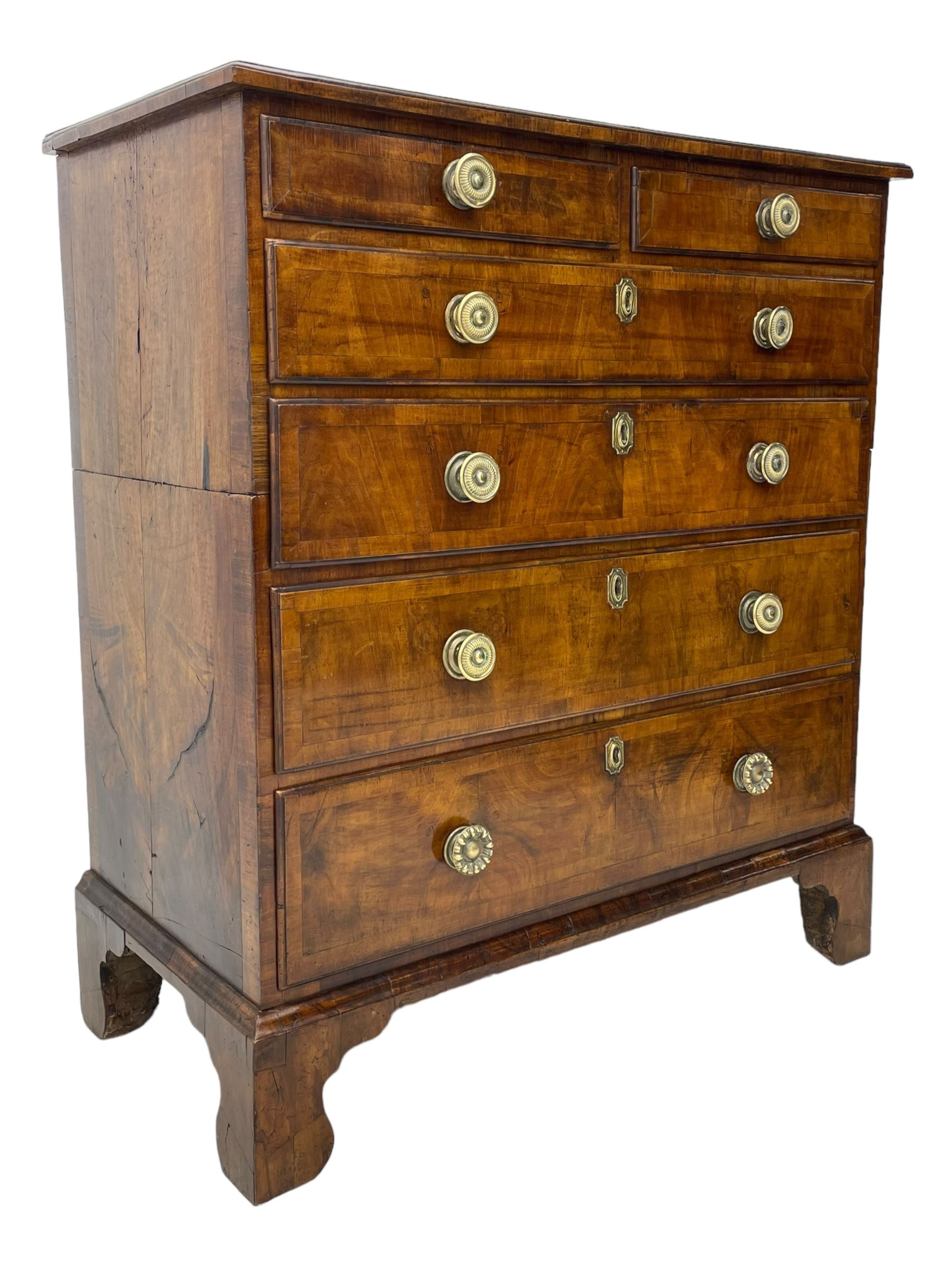 George I walnut chest, moulded rectangular top with book-matched veneers within crossbanding, fitted with two short over four long graduating drawers, moulded drawer fronts with brass handles, on bracket feet, the chest will split into two sections 