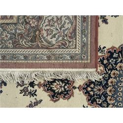 Persian design ivory ground rug, the field decorated with an oval medallion filled with floral motifs and scrolling vines, flanked by floral sprays and corner spandrels with palmette designs, the main border featuring a series of stylised floral patterns against a dark blue ground, enclosed by multiple guard stripes with geometric and floral motifs