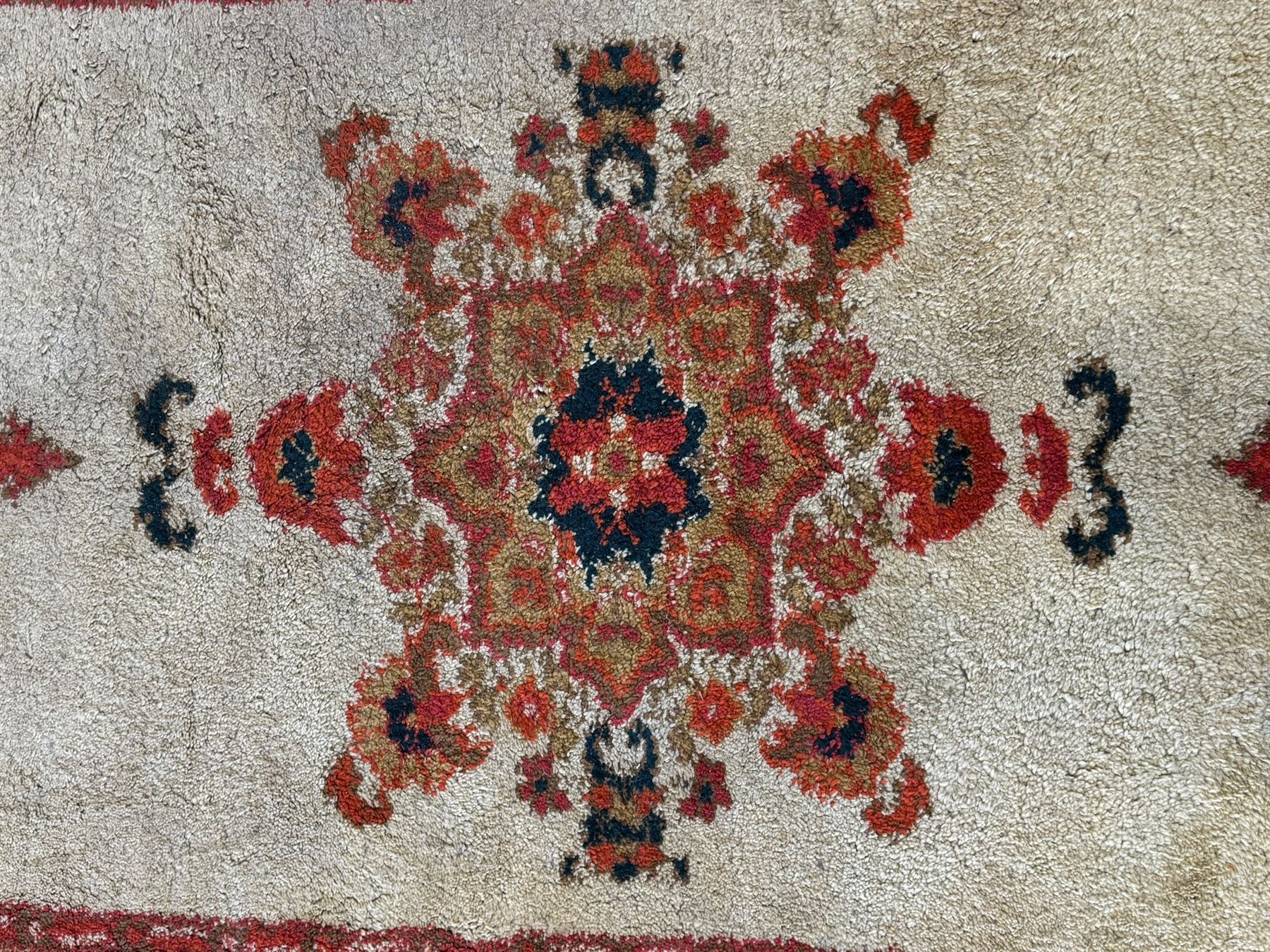 Moroccan amber ground thick pile rug, the plain ivory field decorated with a central pole medallion of star form, the wide guard bands decorated with repeating geometric and foliate patterns