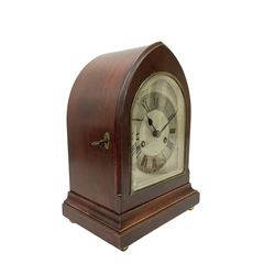German - 8-day Mahogany mantle clock c1910, in a lancet shaped case on a narrow plinth with brass feet, silvered sheet dial with an engraved chapter ring, Roman numerals and steel spade hands,  with a recoil anchor escapement and rack striking movement sounding the hours and half hours on a coiled gong. With pendulum and key. 