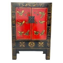 20th century Chinese black lacquered cabinet, rectangular body with two doors enclosing single shelf interior, adorned with gilt butterfly and floral motifs against a red backdrop, standing on square supports