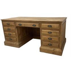 20th century waxed pine kneehole desk, rectangular top over nine drawers with cup handles, on moulded plinth base