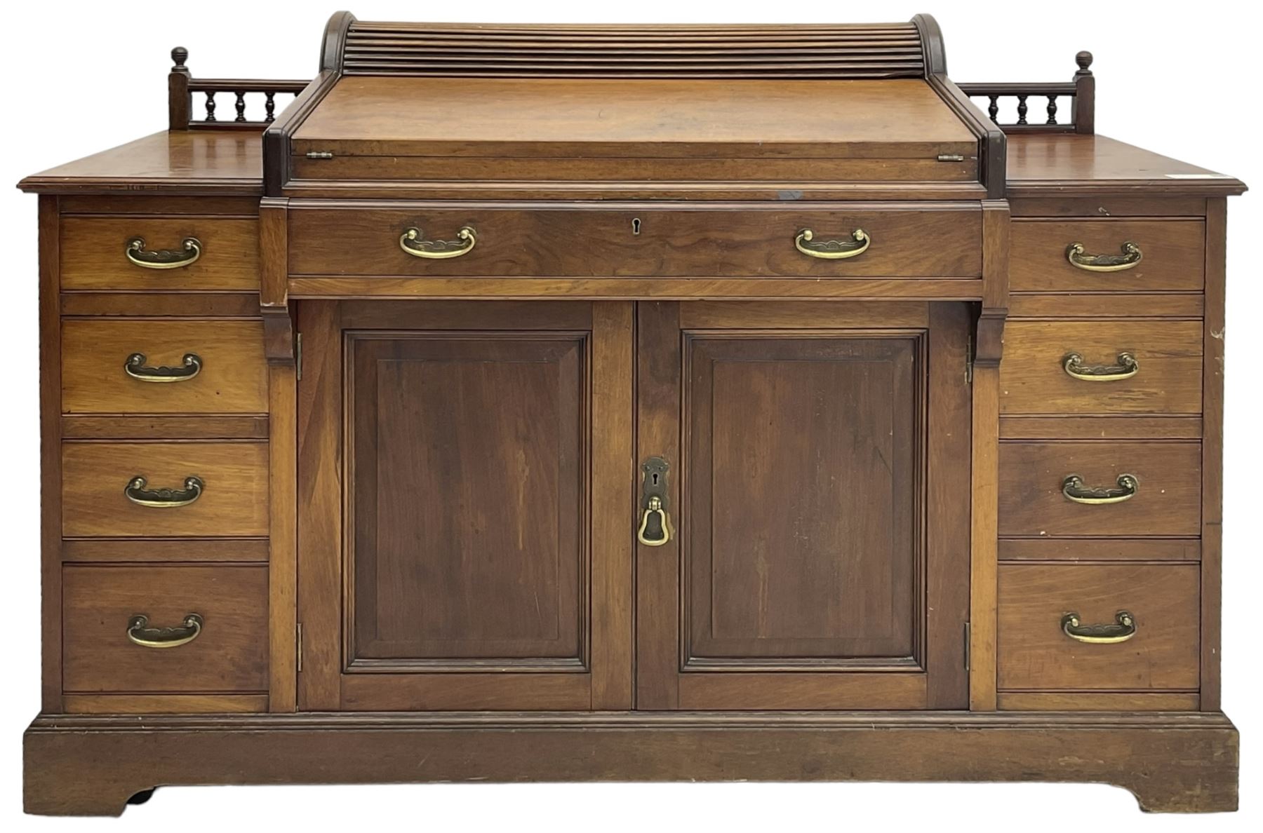 Victorian walnut clerk's desk, raised central section with tambour roll over hinged top, the interior fitted with leather inset writing surfaces, small drawers, document divisions and pen and ink stand, central drawer over double panelled cupboard, flanked by two banks of four graduating drawers, on bracket feet 