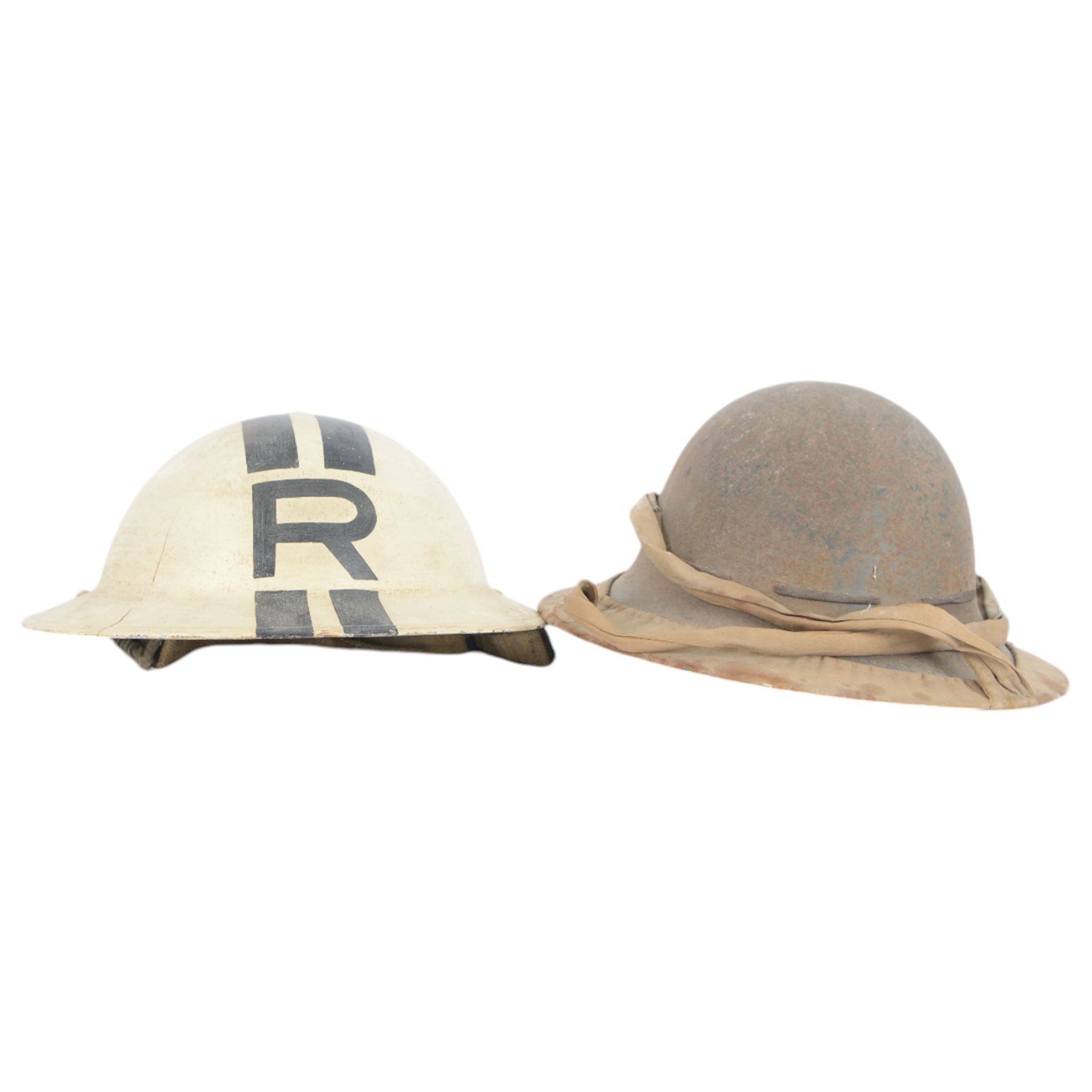 Two WWII British brodie helmets, one example painted white with a black R tot eh front and back, with neck strap  