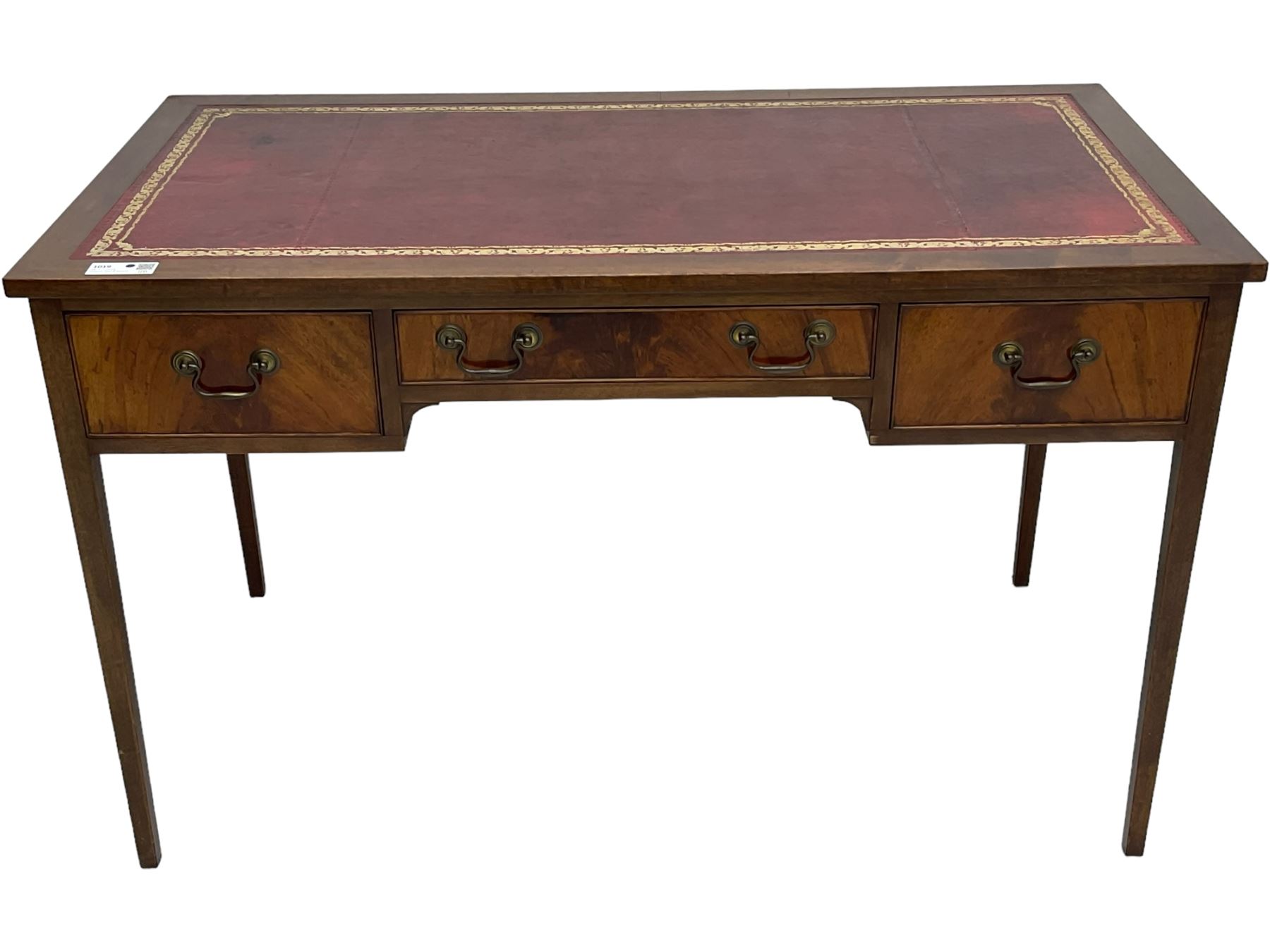 Mid-to-late 20th century mahogany writing desk, the rectangular top with a tooled red leather insert bordered with gilt detailing, three cock-beaded drawers with brass handles, the narrow central drawer flanked by two wider drawers, standing on square tapered legs