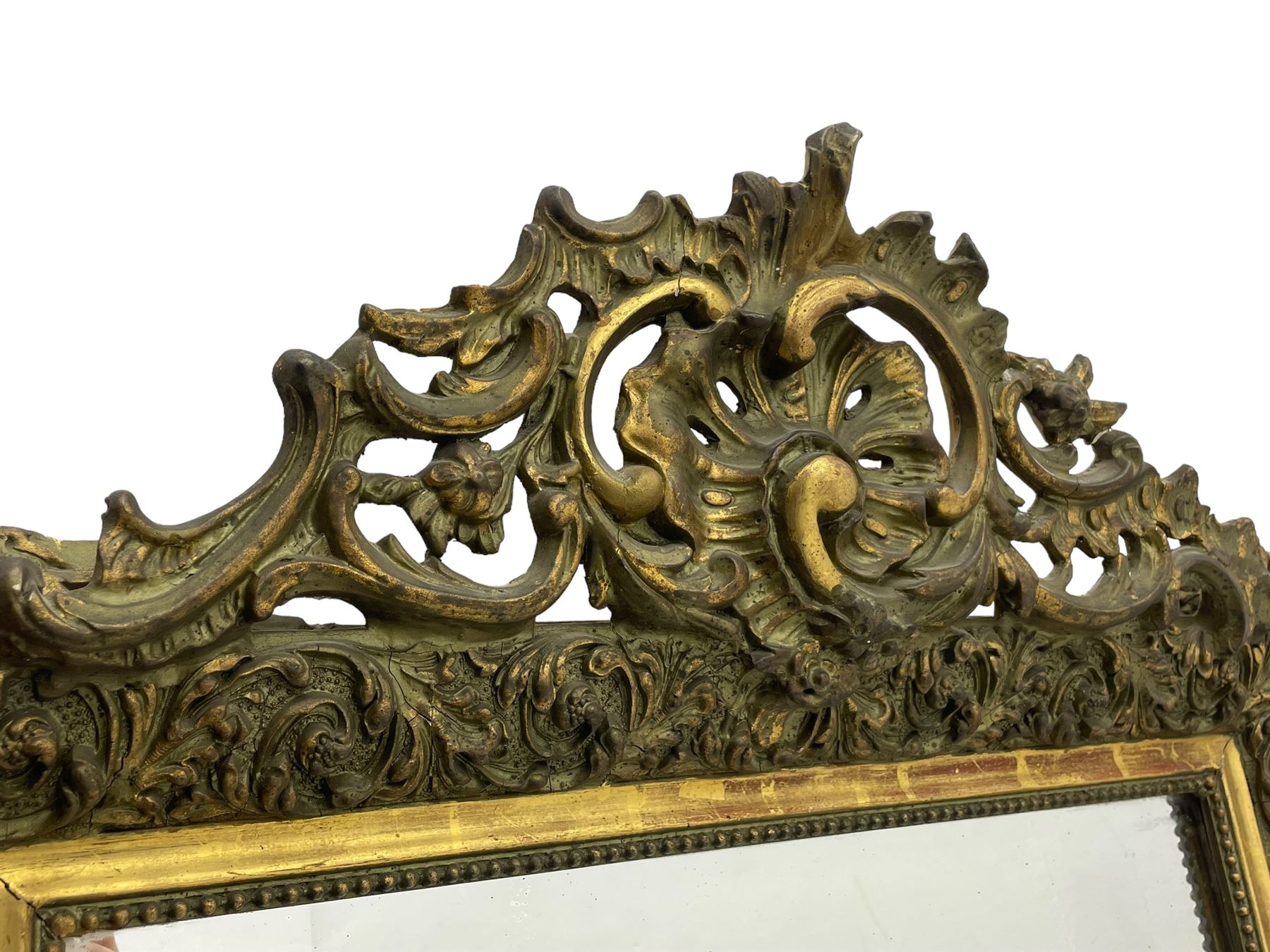 Victorian giltwood and gesso wall mirror, pierced shell cartouche pediment decorated with C-scrolls and curled leaves, moulded frame with curled acanthus leaf decoration and beaded inner slip, the corner brackets decorated with flower heads 