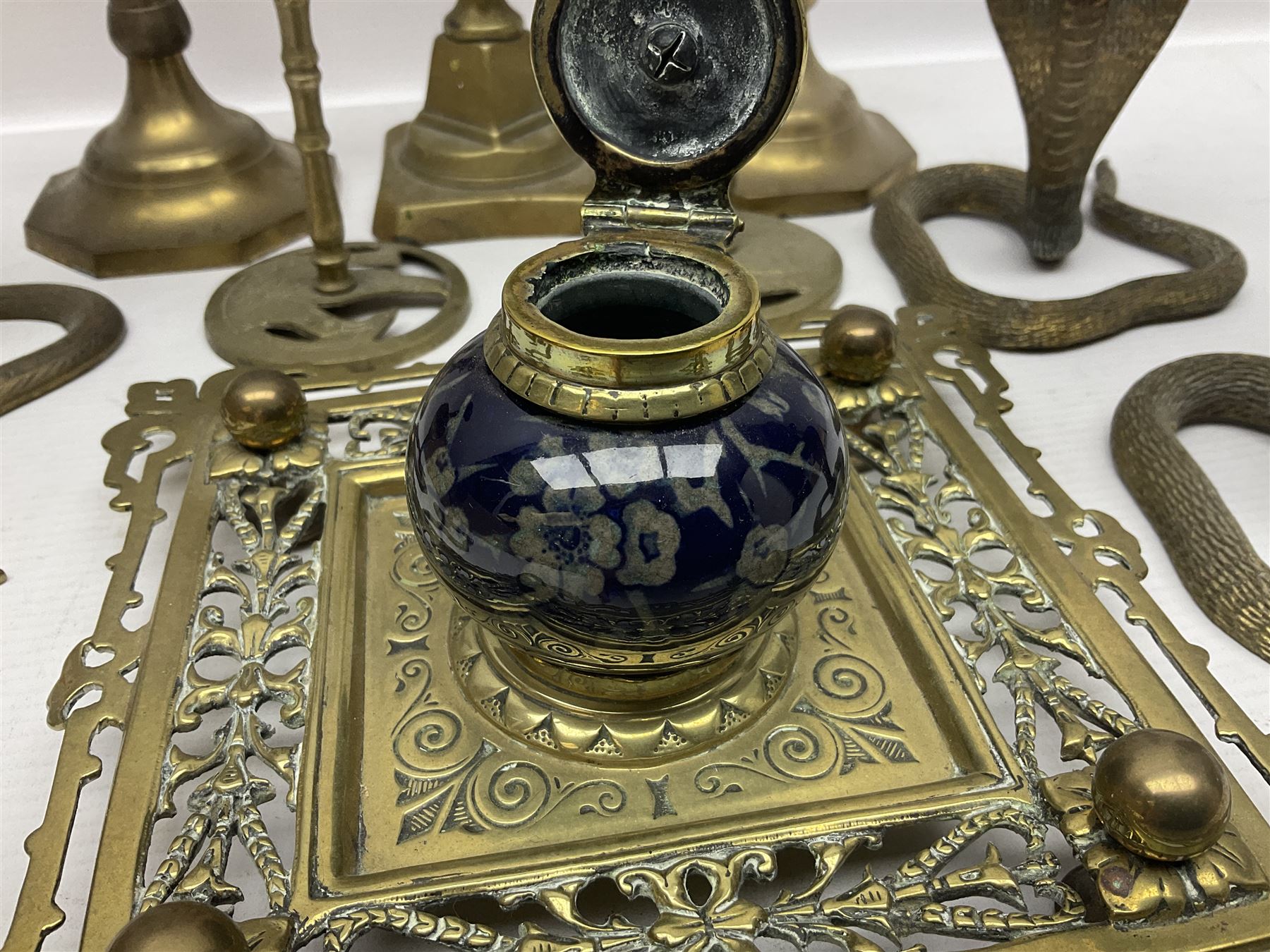 Brass inkstand, of square form, pierced, inset with blue and white ceramic inkwell to centre, together with a collation of brass candlesticks 