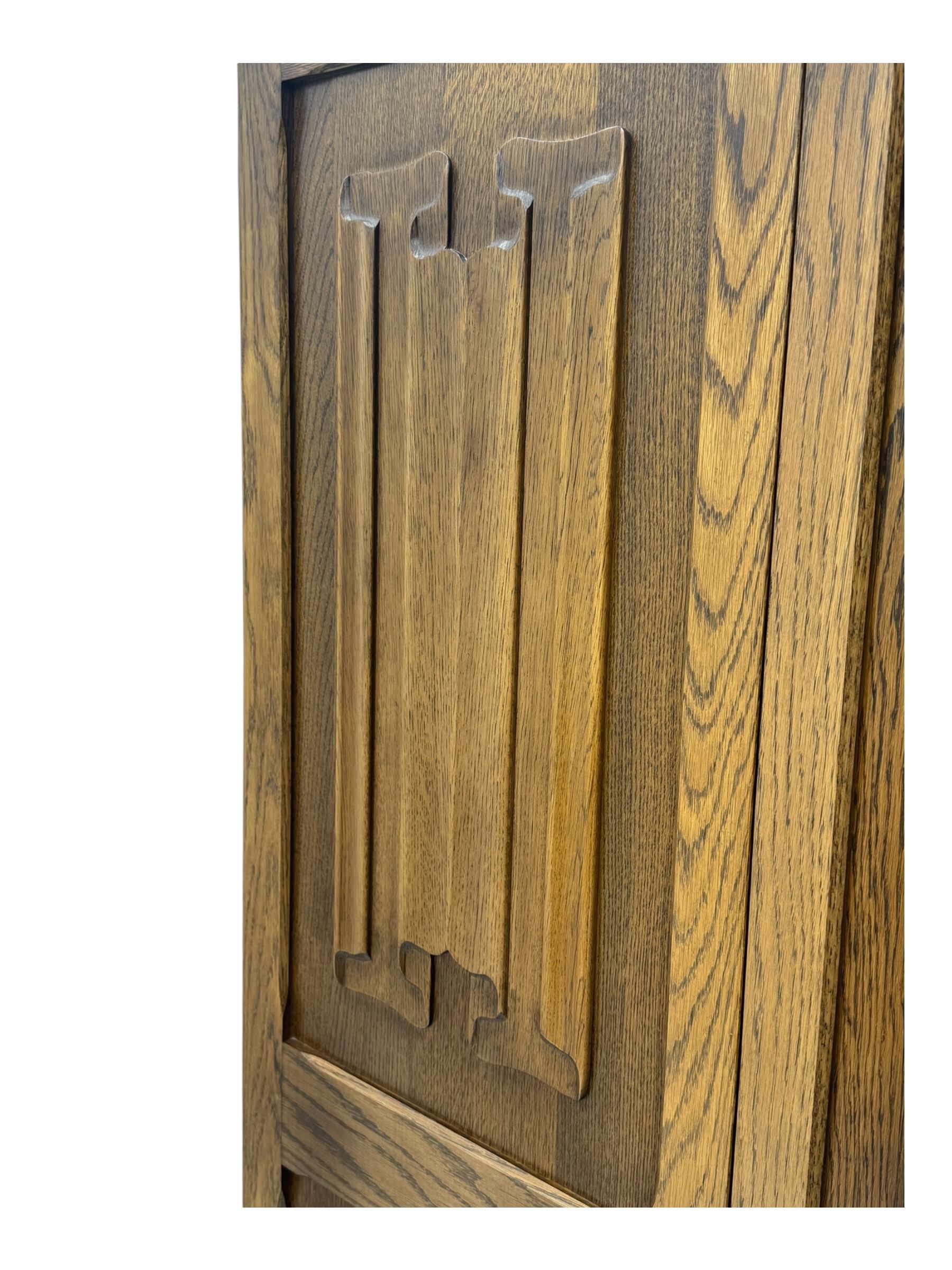 Jacobean design oak double wardrobe, projecting cornice over Gothic arched tracery carved frieze, twin panelled doors with linenfold relief carved detailing, on plinth base