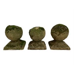 Set of three weathered cast stone gate post finials, circular orb on step-canted square base 