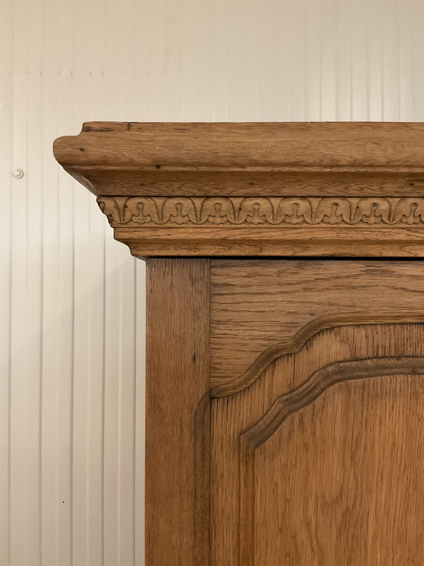 Late 19th century oak triple wardrobe, wide central bevelled mirror door, flanked by two panelled doors each carved with scrolling leaves and flower heads, on moulded skirt base 