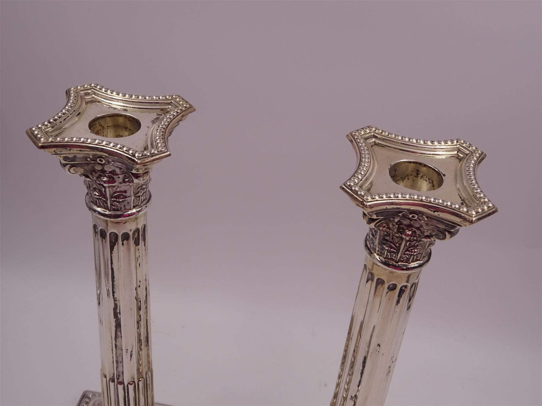 Pair of modern silver Corinthian column candlesticks, each with removable sconces with dart edging and embossed detailing, with personal engraving in a Semitic language, upon weighted stepped square bases, hallmarked Birmingham 1962, maker's marks HYC, H30.5cm