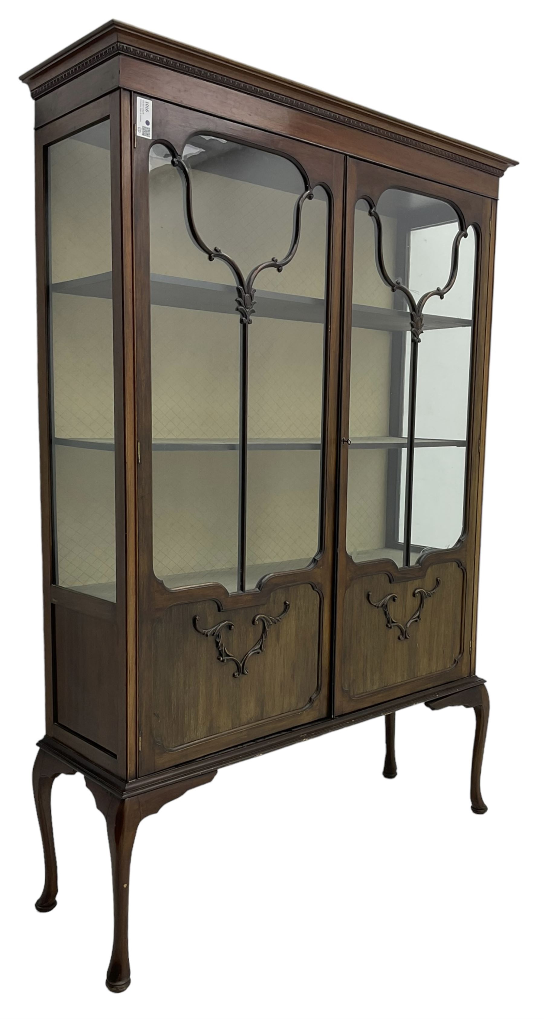 Early 20th century mahogany straight-front display cabinet, projecting moulded cornice over two astragal glazed doors with lower panels, on cabriole supports 