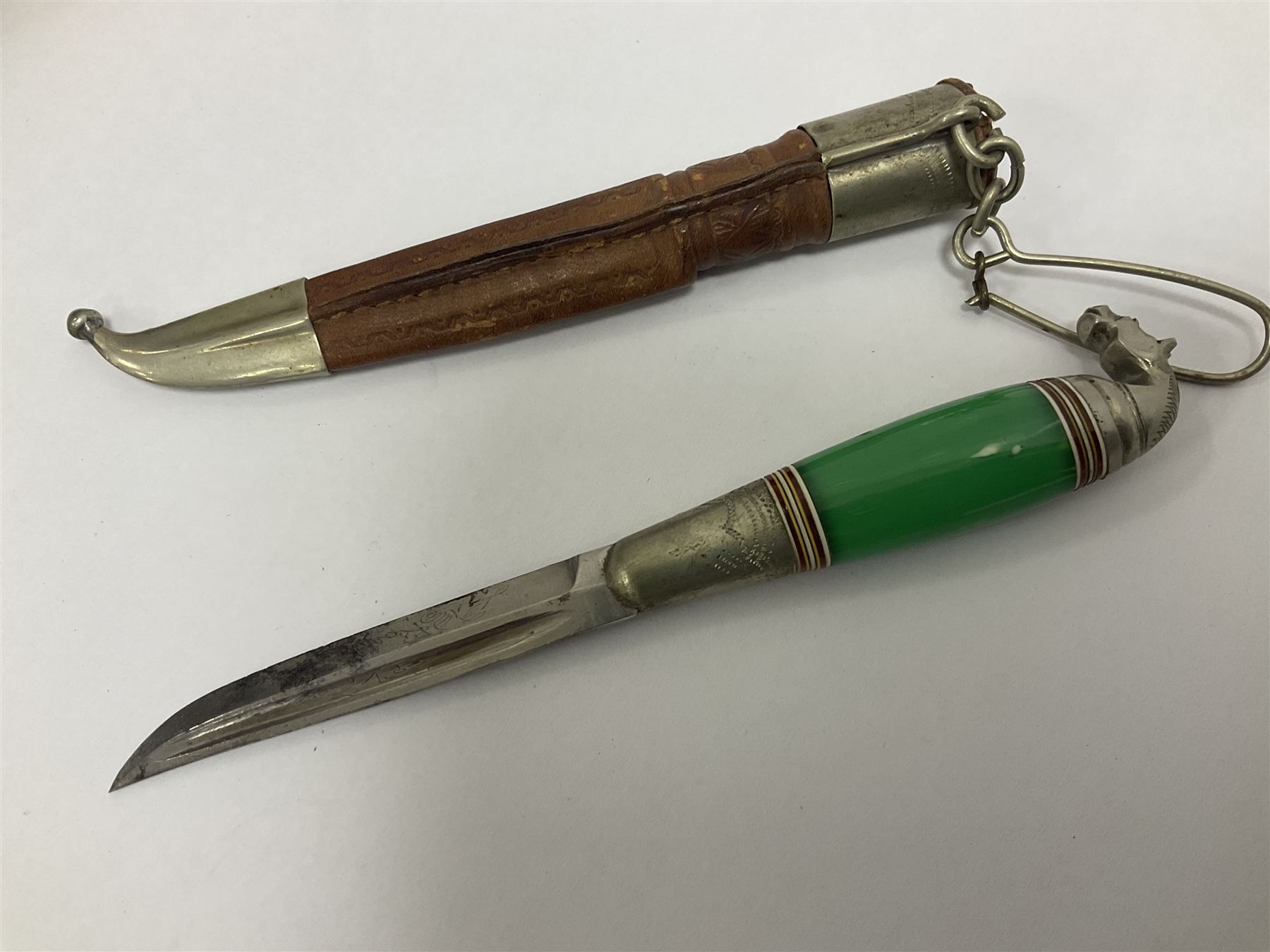 Two Scandinavian bowie knives, the first example with polished green handle with horse head final in white metal, with brown leather sheath, blade L6cm overall L12cm, the second with a polished bone handle, in black sheath with white metal tip, blade L11cm overall 23cm