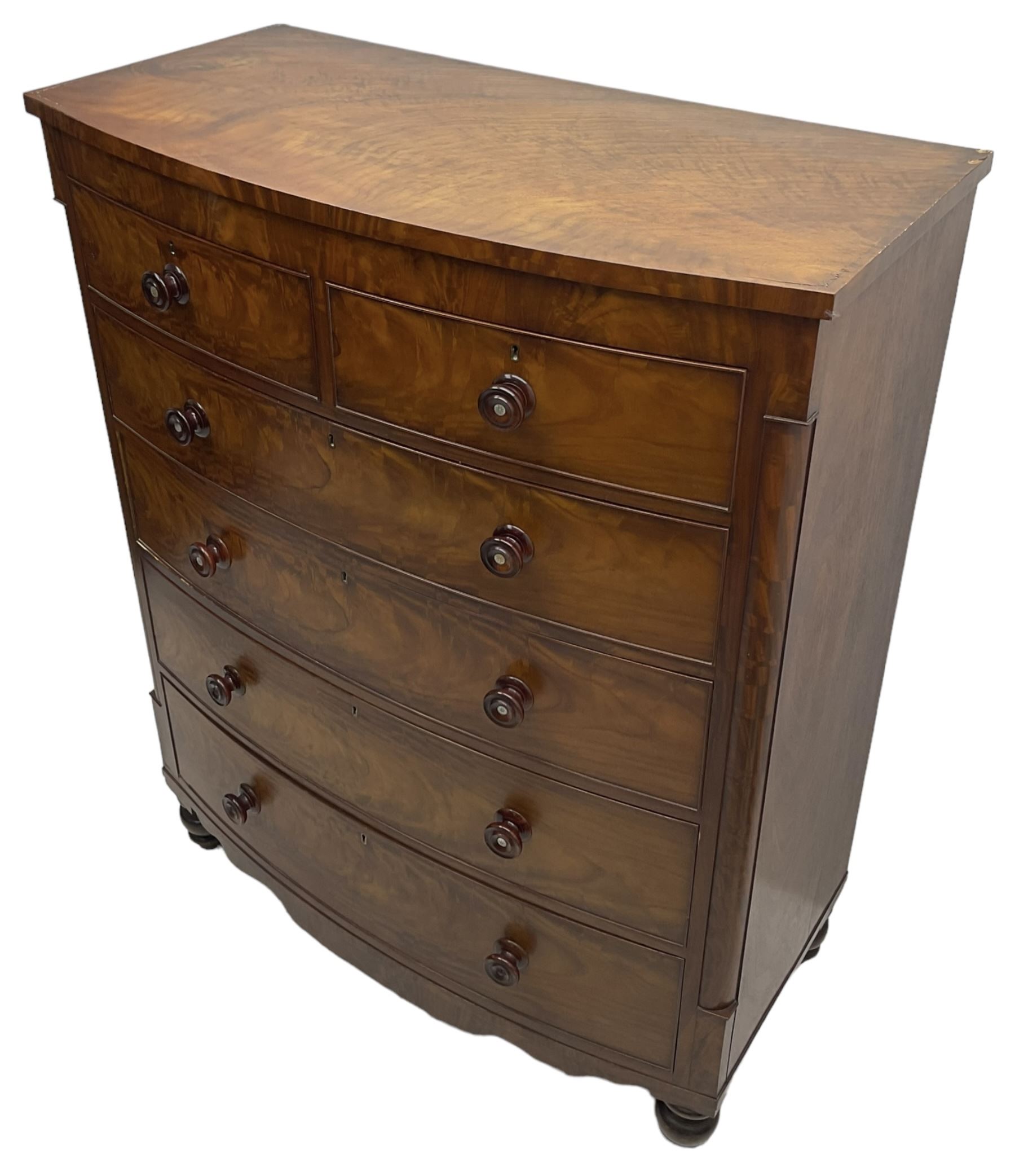 Tall Victorian mahogany bow-front chest, fitted with two short over four long cock-beaded drawers, with turned handles, canted upright corners with quarter columns, shaped apron, on turned feet