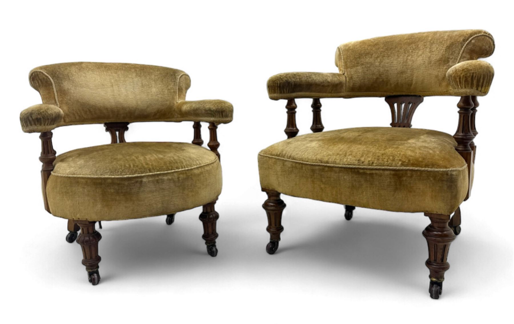 Victorian pair of mahogany armchairs, upholstered in gold velvet fabric, each with curved back, pierced splat and scroll arms, one with rounded seat and the other square, on turned front supports with castors