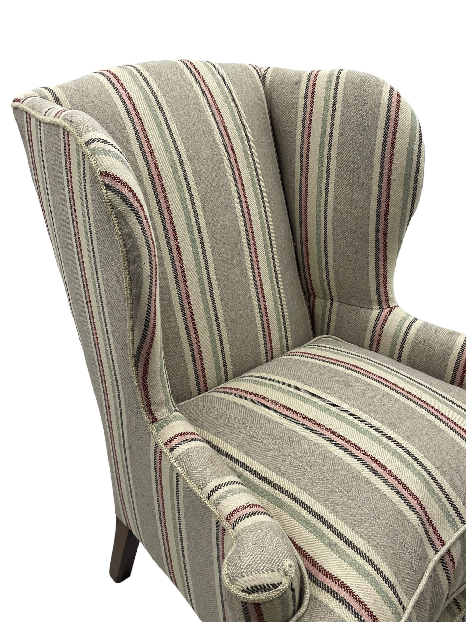 Georgian design hardwood-framed wingback armchair, curved wingback terminating to curved and rolled arms, upholstered in striped fabric with loose seat cushion, on cabriole front feet 