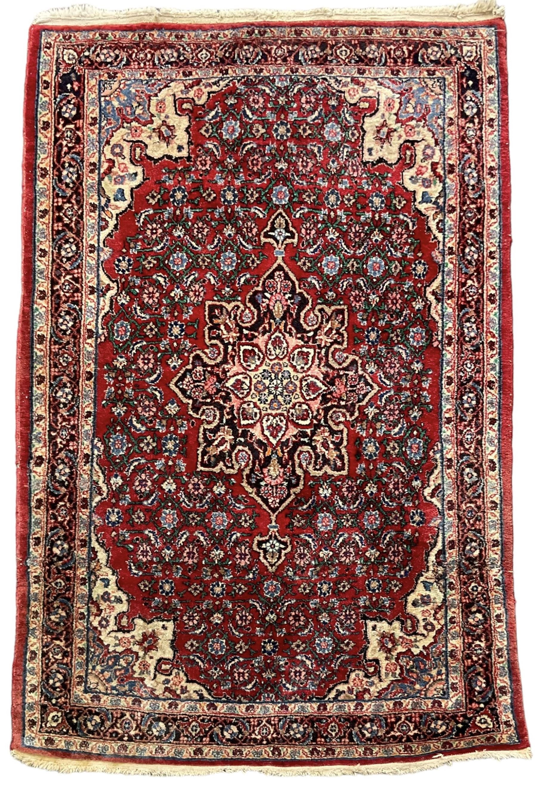 Persian design crimson ground rug, the field decorated with central floral pole medallion and surrounded by foliate patterns with matching spandrels, guarded border with repeating palmette motifs