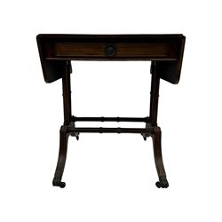 Mahogany drop-leaf sofa table, rectangular top over single frieze drawer with carved rosette handle, twin turned columns united by twin stretchers, on splayed supports terminating in paw feet with castors