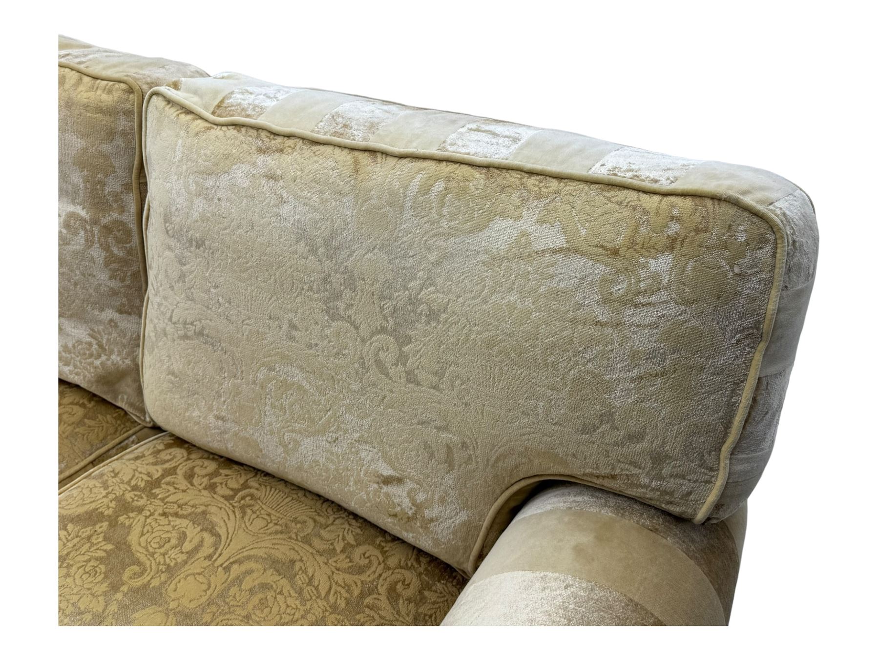 Contemporary two-seat sofa, upholstered in damask fabric with a pale gold floral pattern, rolled arms, loose back and seat cushions, on matching skirted base with concealed castors