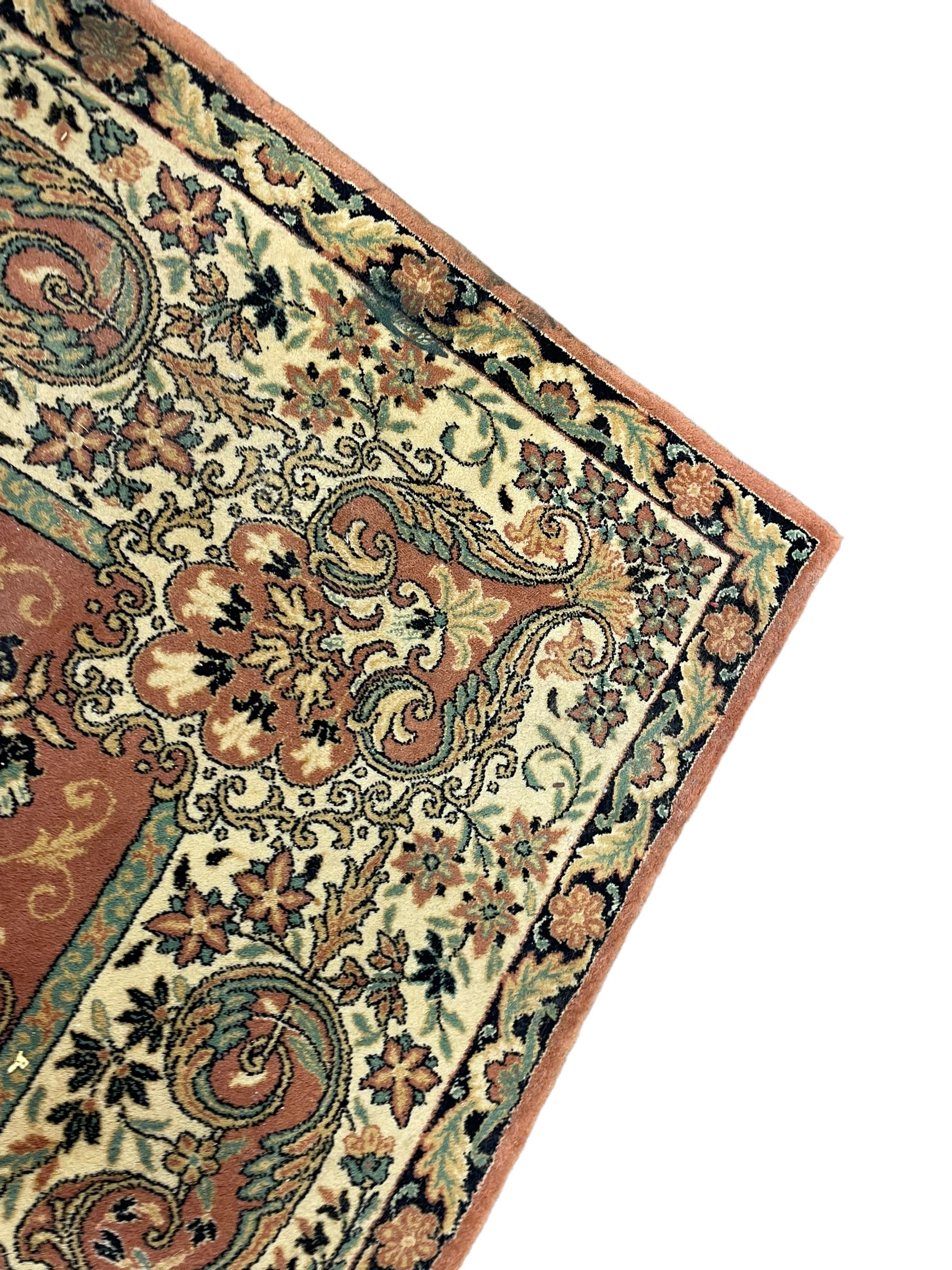 Persian design peach ground carpet, central floral medallion surrounded by scrolling foliage, decorated all over with stylised plant motifs, floral design repeating border