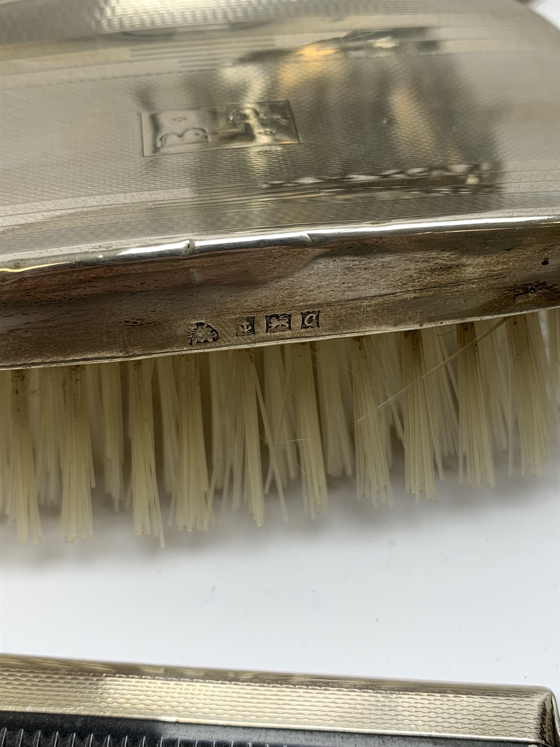 A pair of silver mounted clothes brushes, each with engine turned detail and monogramed central panel, and silver comb mount, all hallmarked Adie Brothers Ltd, Birmingham, date letters worn and indistinct, together with a cased set of six mother of pearl knives with silver ferrules, hallmarked William Yates Ltd, Sheffield 1916, a silver plated bottle coaster, with pierced sleeve and twin handles, marked beneath for Daniel and Arter, Birmingham, and a set of six silver plated coffee bean spoons. 