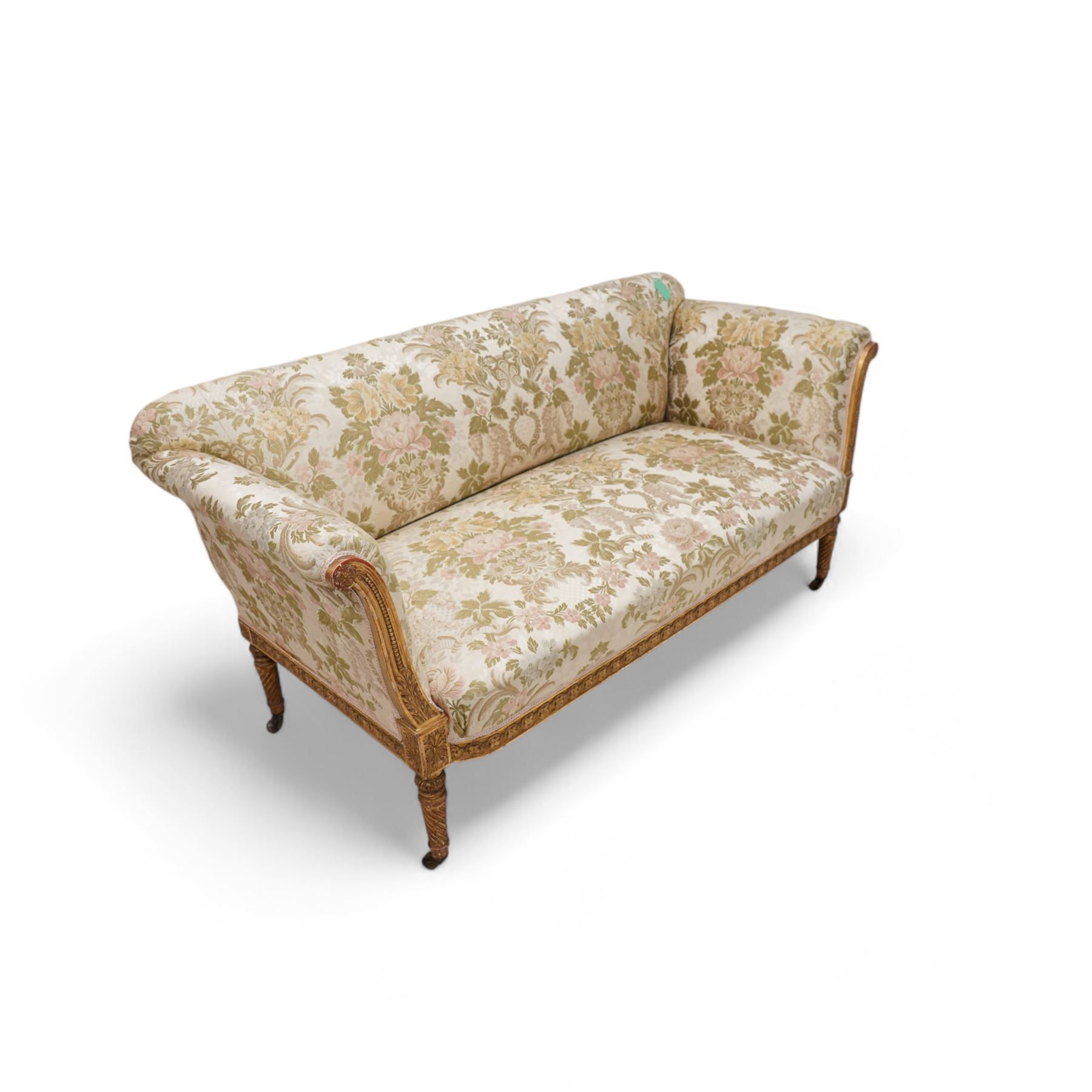 19th century gilt wood and gesso settee, upholstered in repeating floral pattern fabric, rolled arms decorated with trailing bead moulding and acanthus leaf, the seat rail with flower head band, on twist turned and foliate carved feet with brass castors 