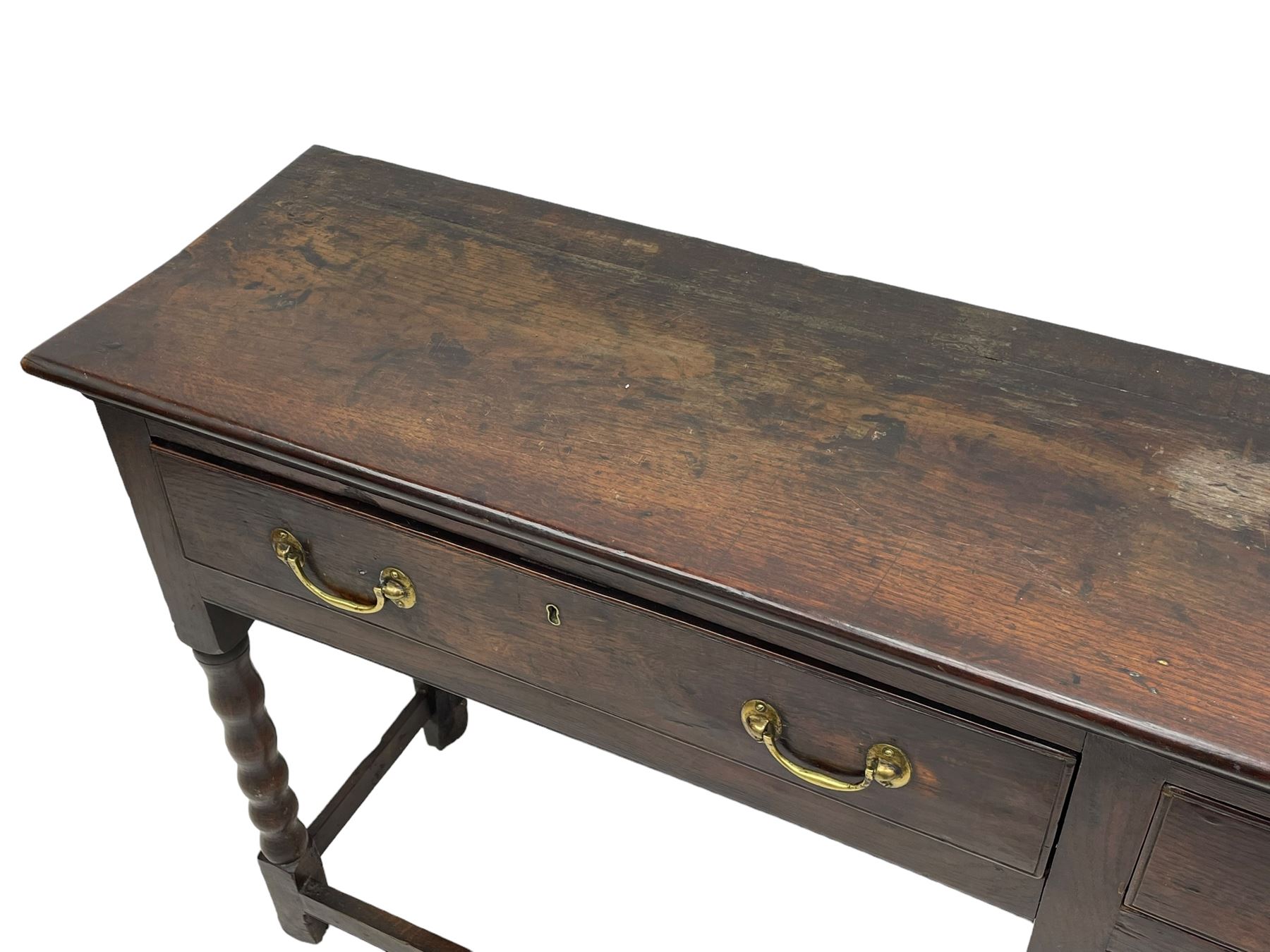 18th century oak dresser base, rectangular top, fitted with two drawers with moulded facia edges and brass swan neck handles, raised on turned front supports united by stretchers