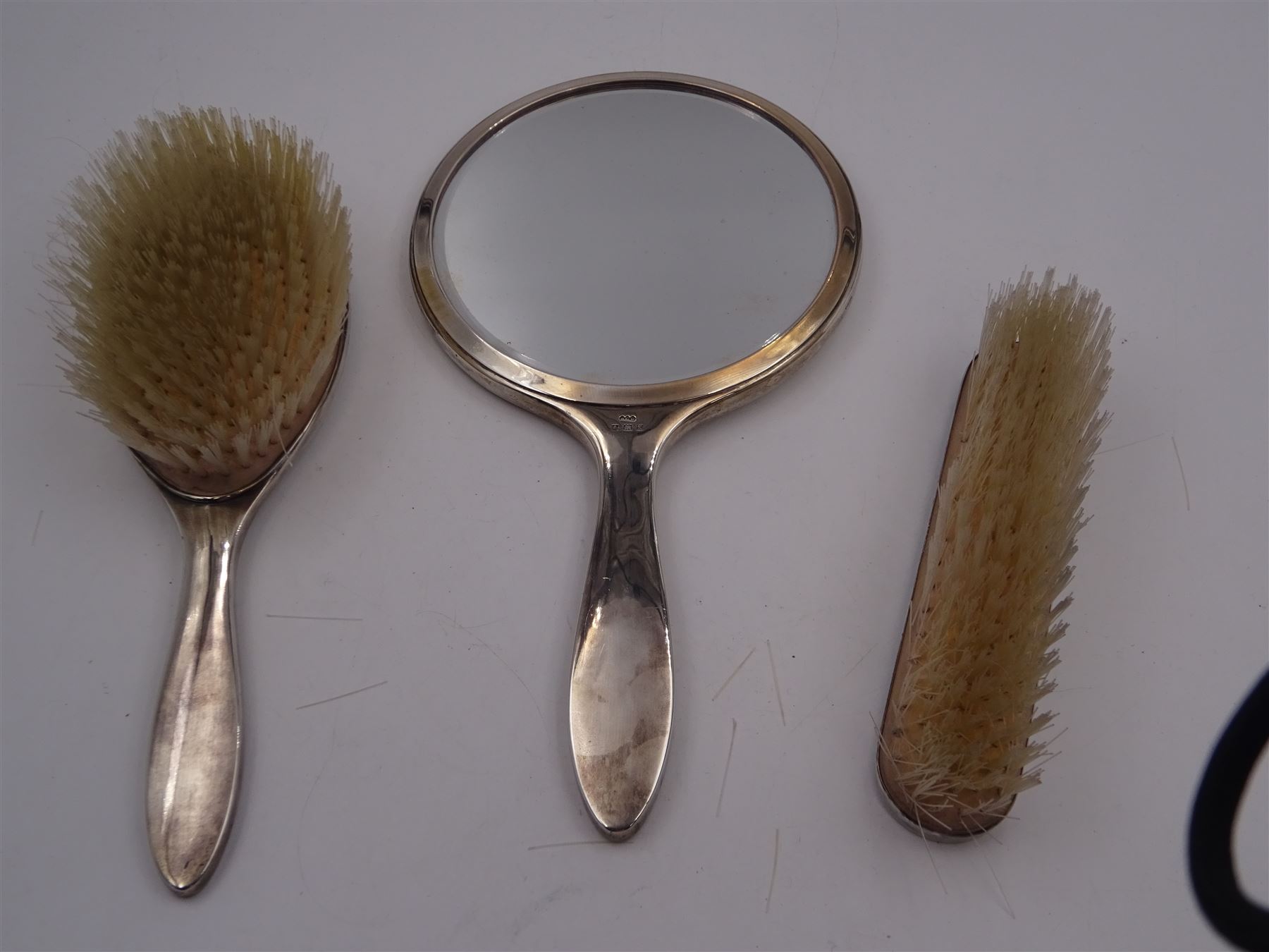 Mid 20th century silver mounted three piece dressing table set, comprising hand mirror, hair brush and clothes brush, each with white guilloche enamel decoration and set with a carved green hardstone, hallmarked Henry Clifford Davis, Birmingham 1959