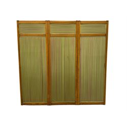 Edwardian oak and fabric folding screen, featuring three panels with oak frames, one side covered in green striped fabric with decorative trim, the reverse side in pink moiré effect fabric, connected by brass hinges