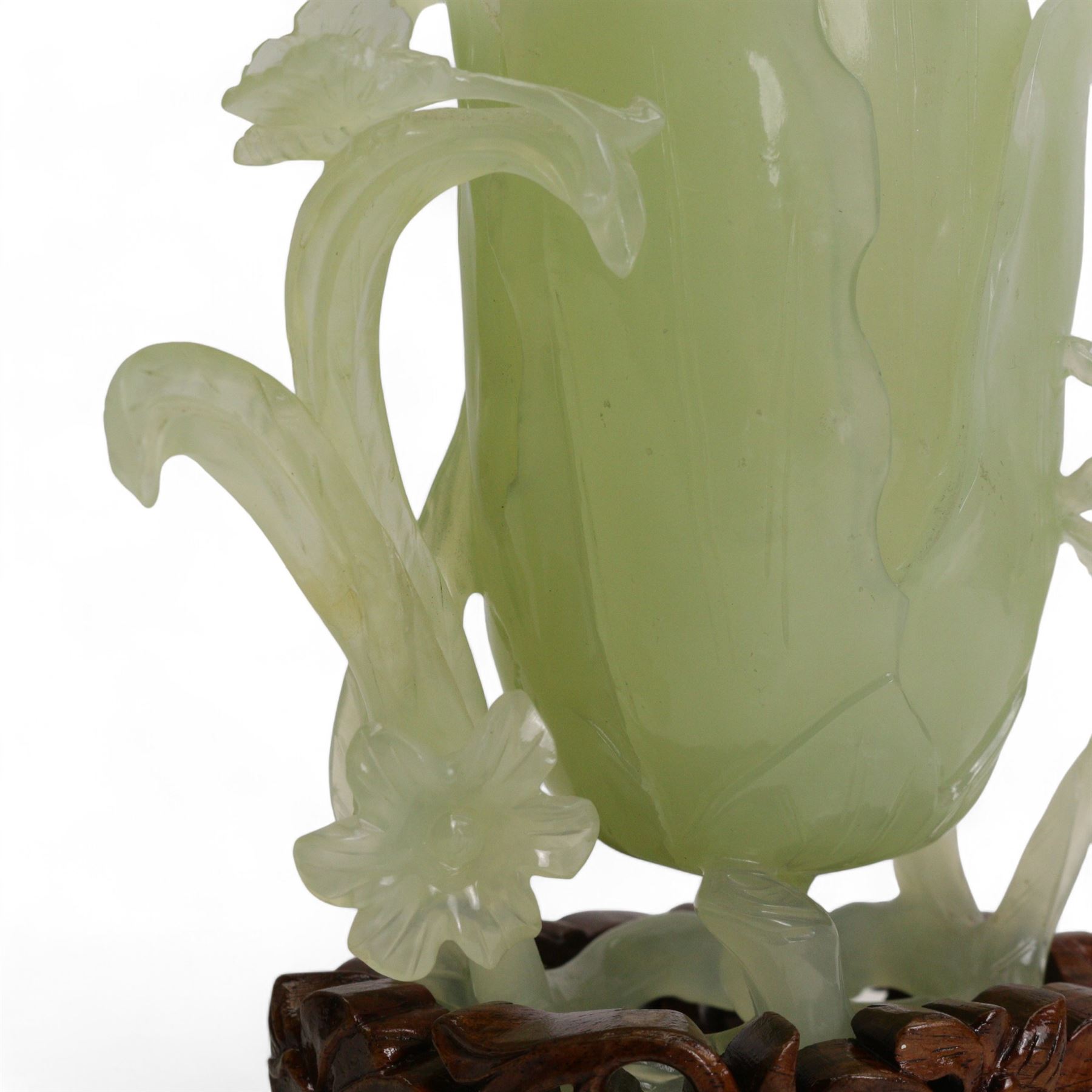 Chinese green jade magnolia form vase, supported on a leafy stem, with flowers and butterflies, on a pierced and carved hardwood stand, H15cm x W14cm